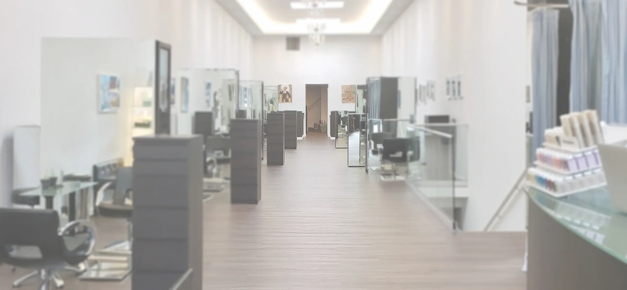 Empty modern office or art gallery with desks, chairs, paintings on the walls, and a floor with wooden planks.