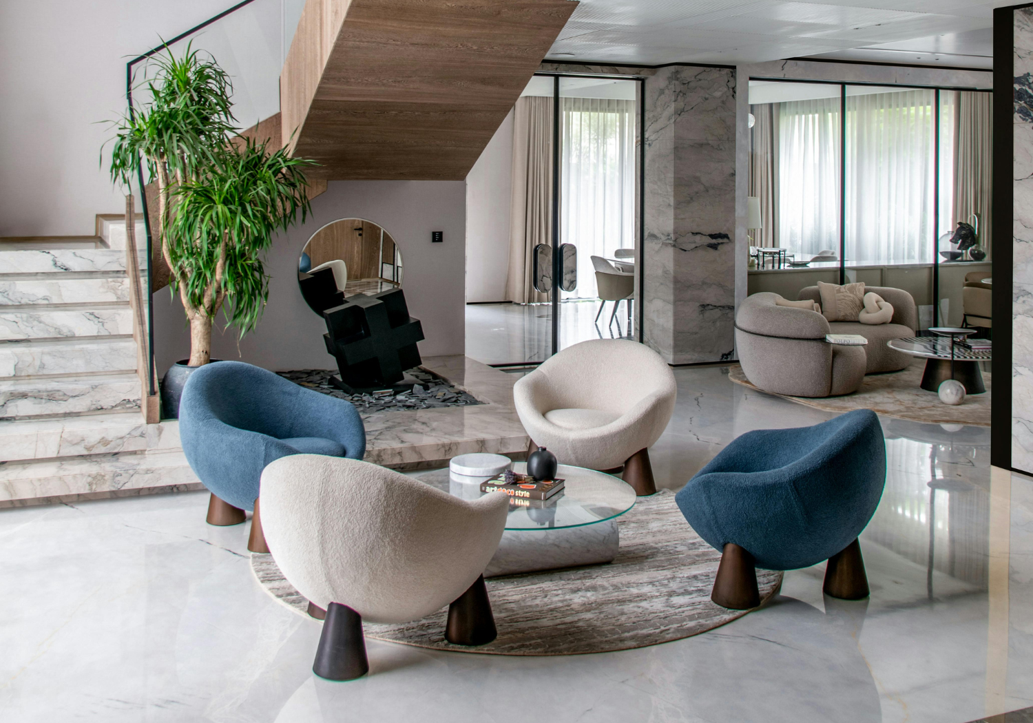 Modern interior living room with marble flooring, abstract chairs around a glass coffee table, a large potted plant, and a sitting area with a curved sofa near glass walls with curtains.