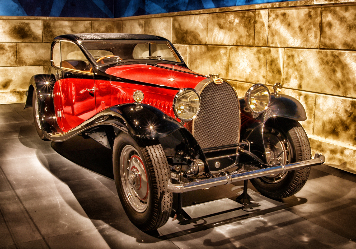 A vintage red and black Bugatti car displayed in a museum