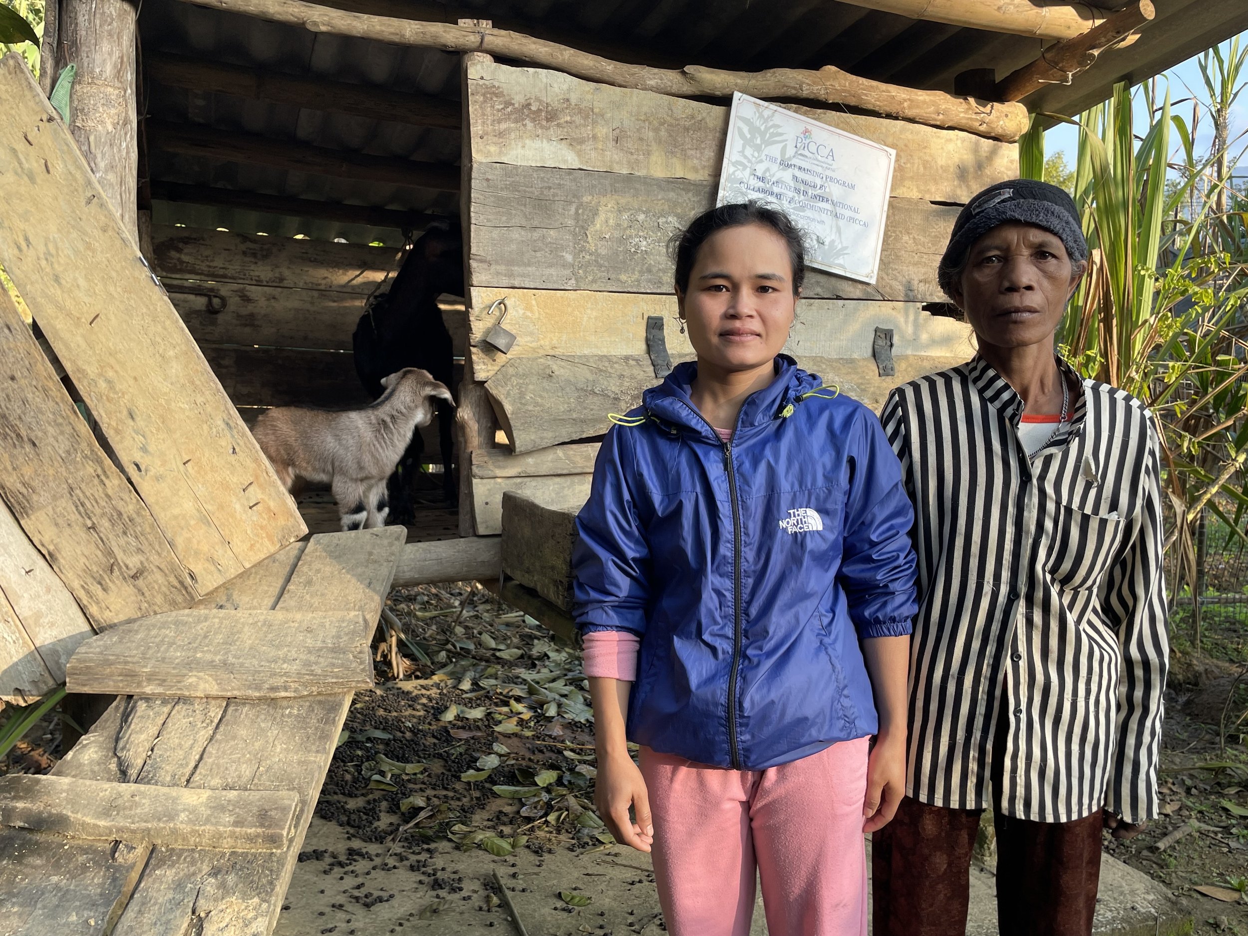 Mother and daughter standing outside their goat shed