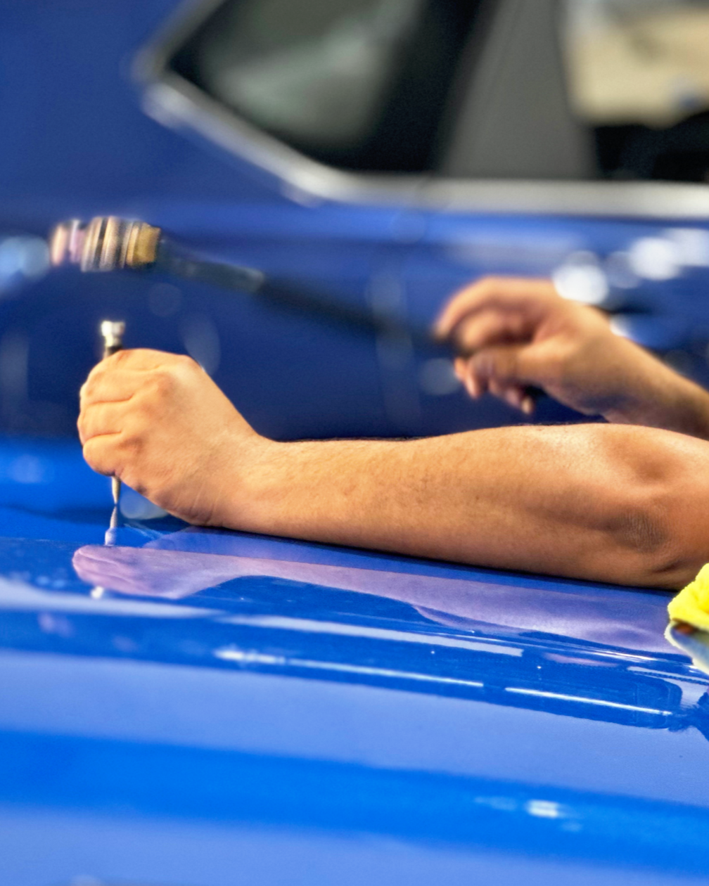 The owner of Hail Repair Experts Paintless Dent Repair on a blue car