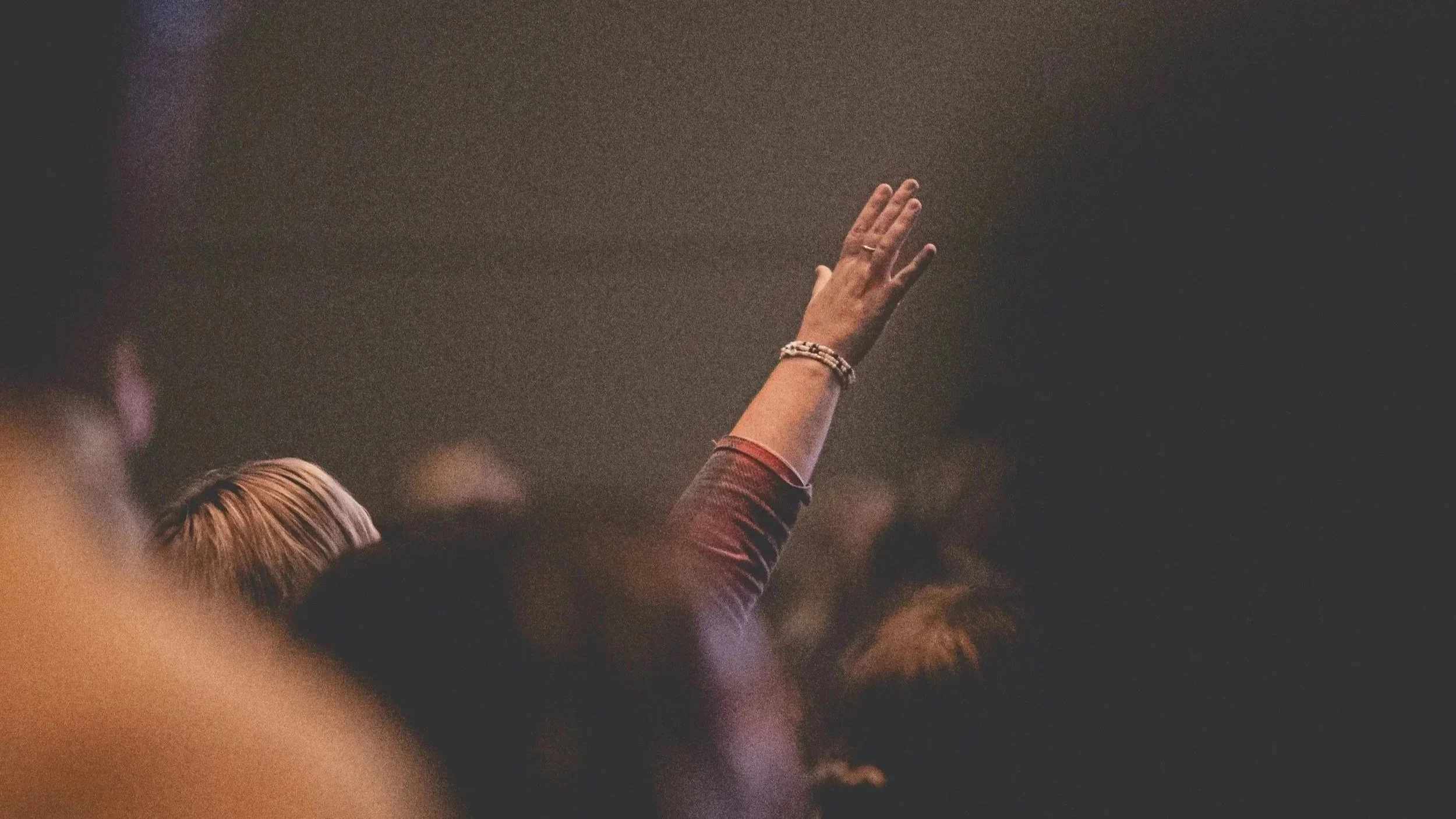 Person with raised hand at a crowded event or gathering.