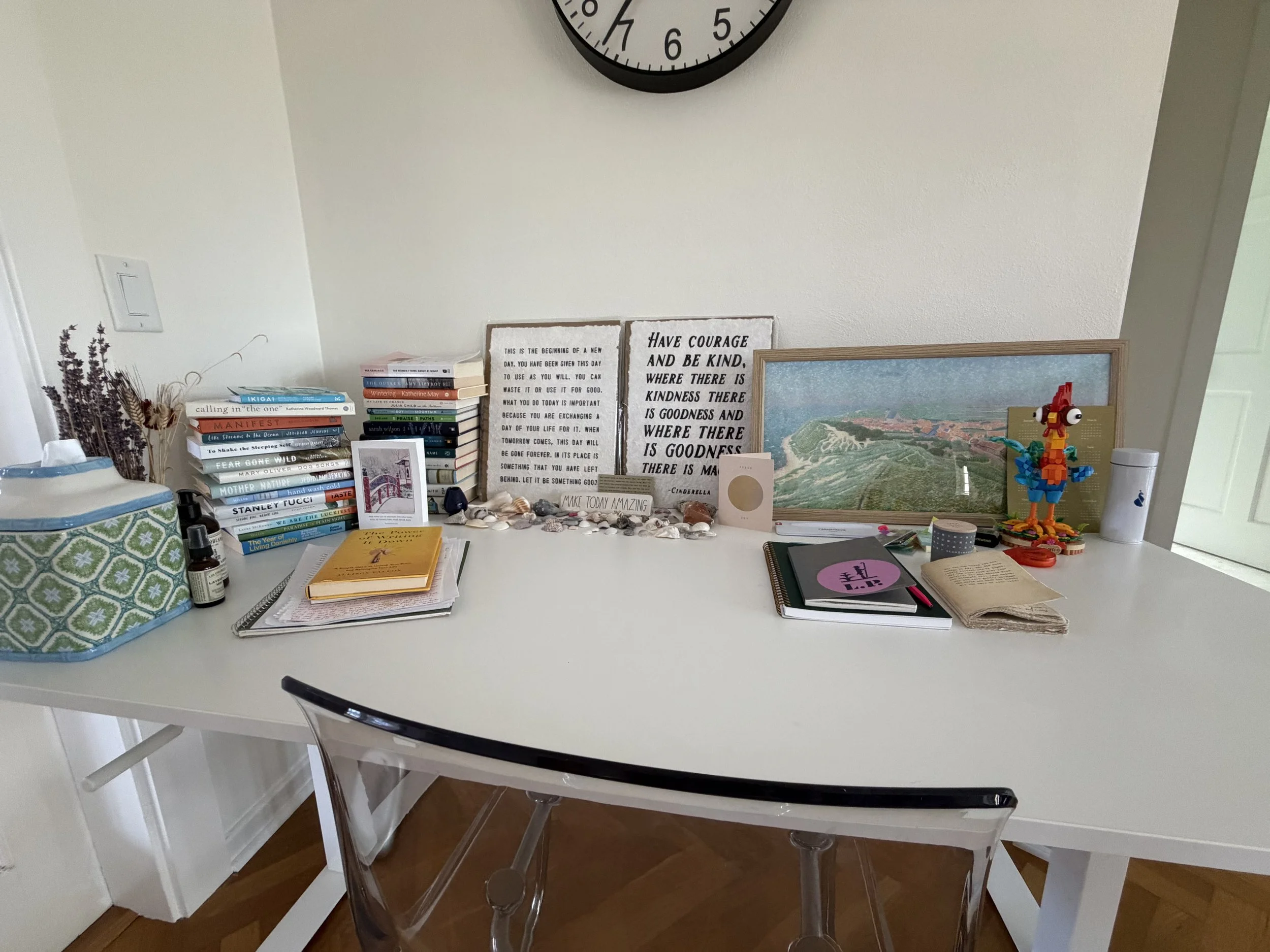 Author's writing desk with a stack of books, rocks from Petoskey, MI and shells from Vero Beach.