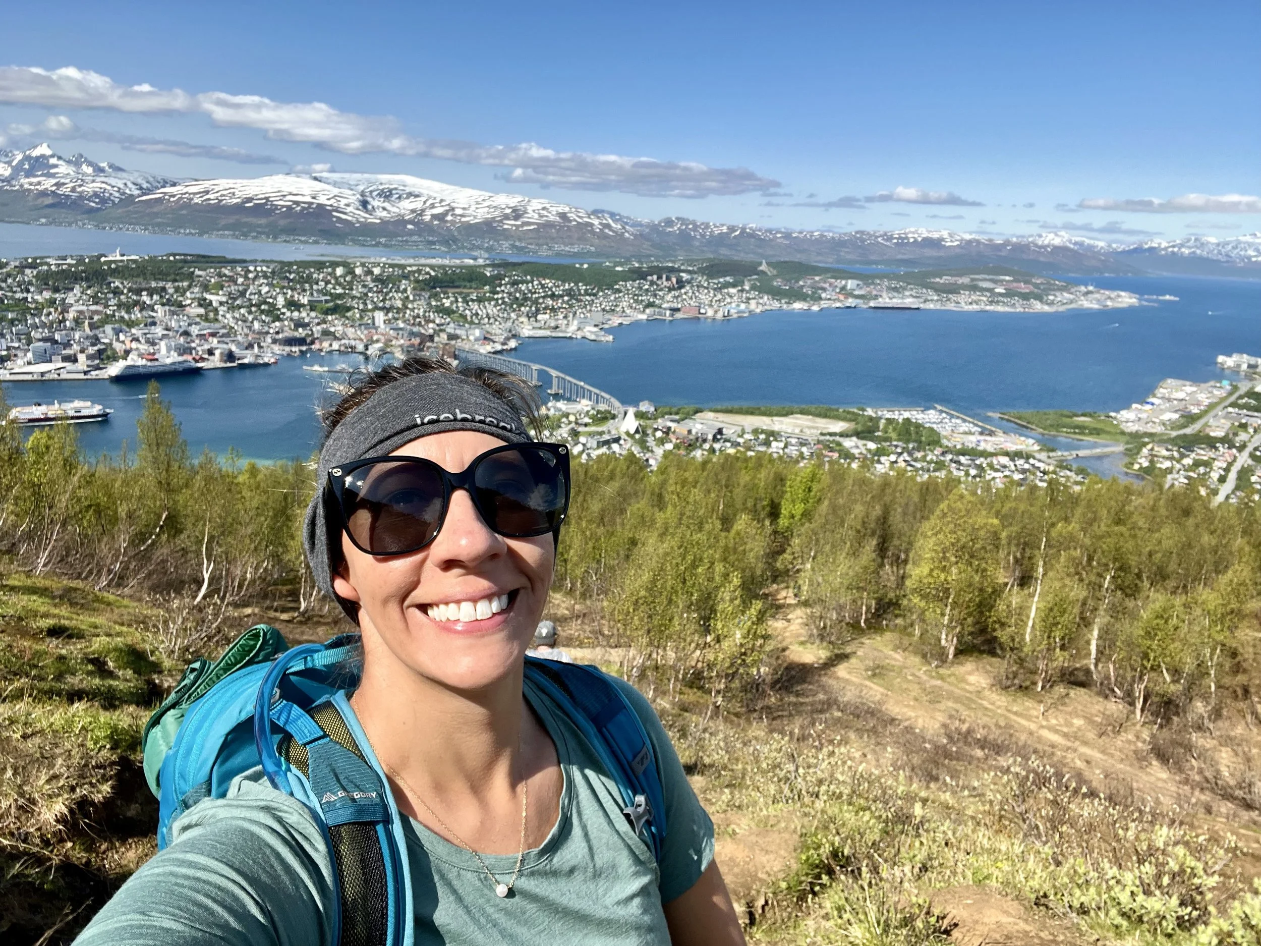 Woman standing on a mountain top with Tromso, Norway in the background