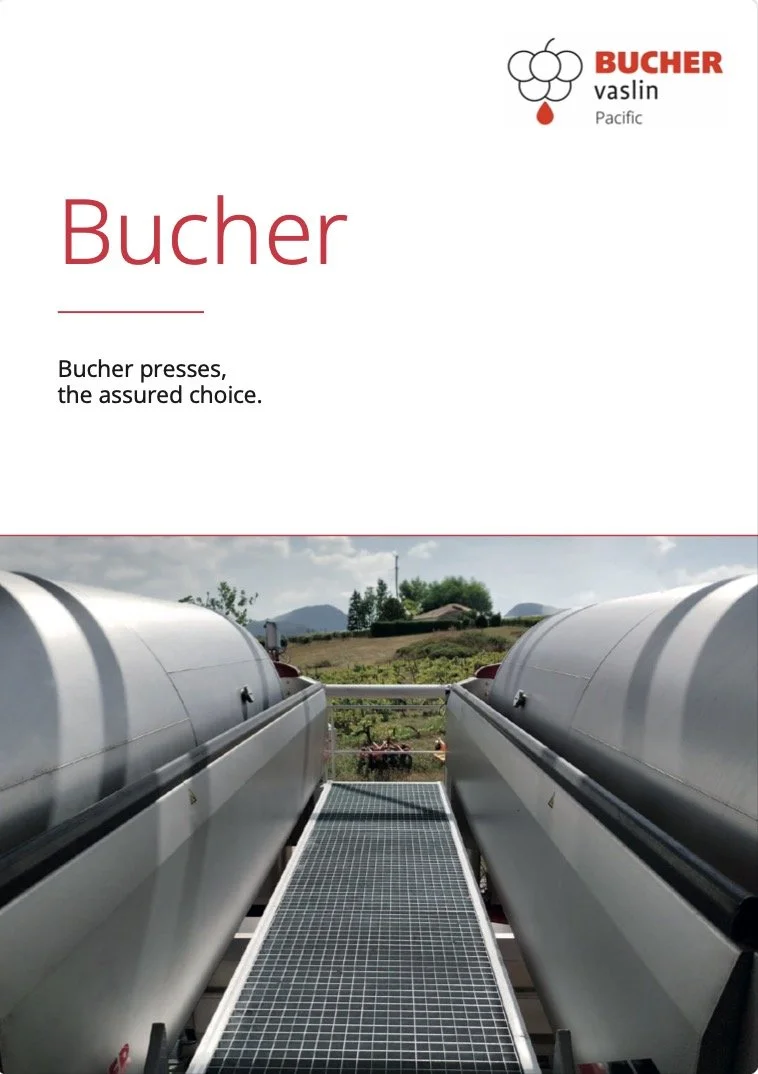 Two large industrial tanks connected by a walkway, with a rural landscape of fields, trees, and mountains in the background.