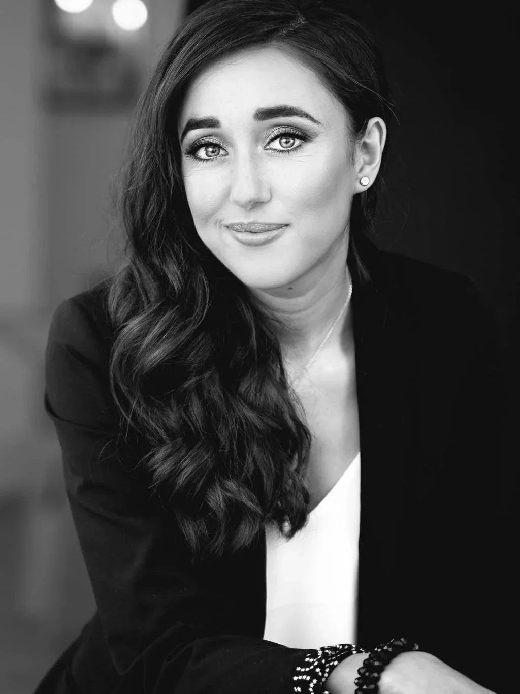 Black and white portrait of Adelaide City Singers director, Jyoti Singh, smiling slightly at the camera