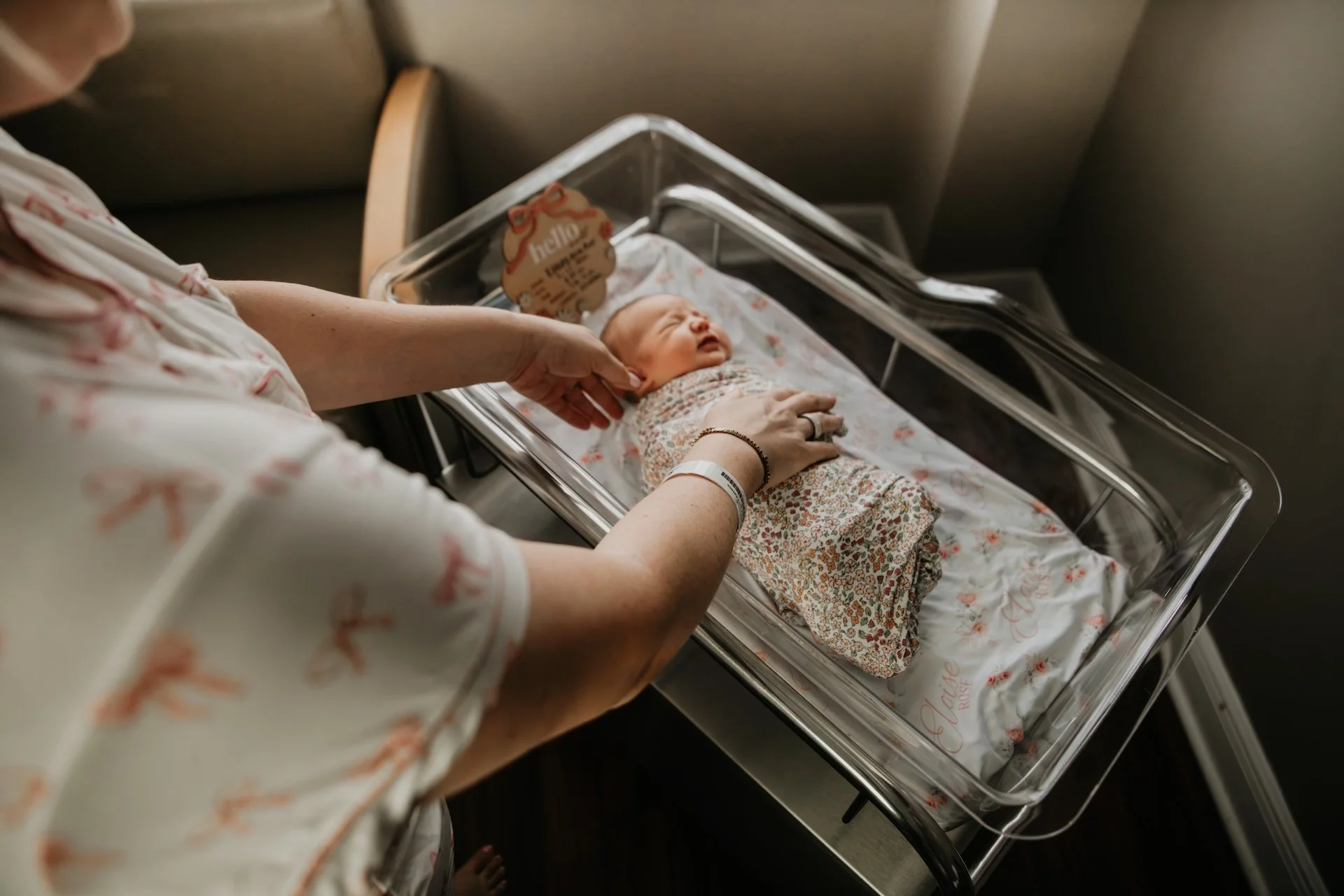 A newborn baby lying in an incubator with a woman gently touching the baby's head in a hospital. L'objectif Photography: New Orleans Wedding, Event, and Portrait Photographer