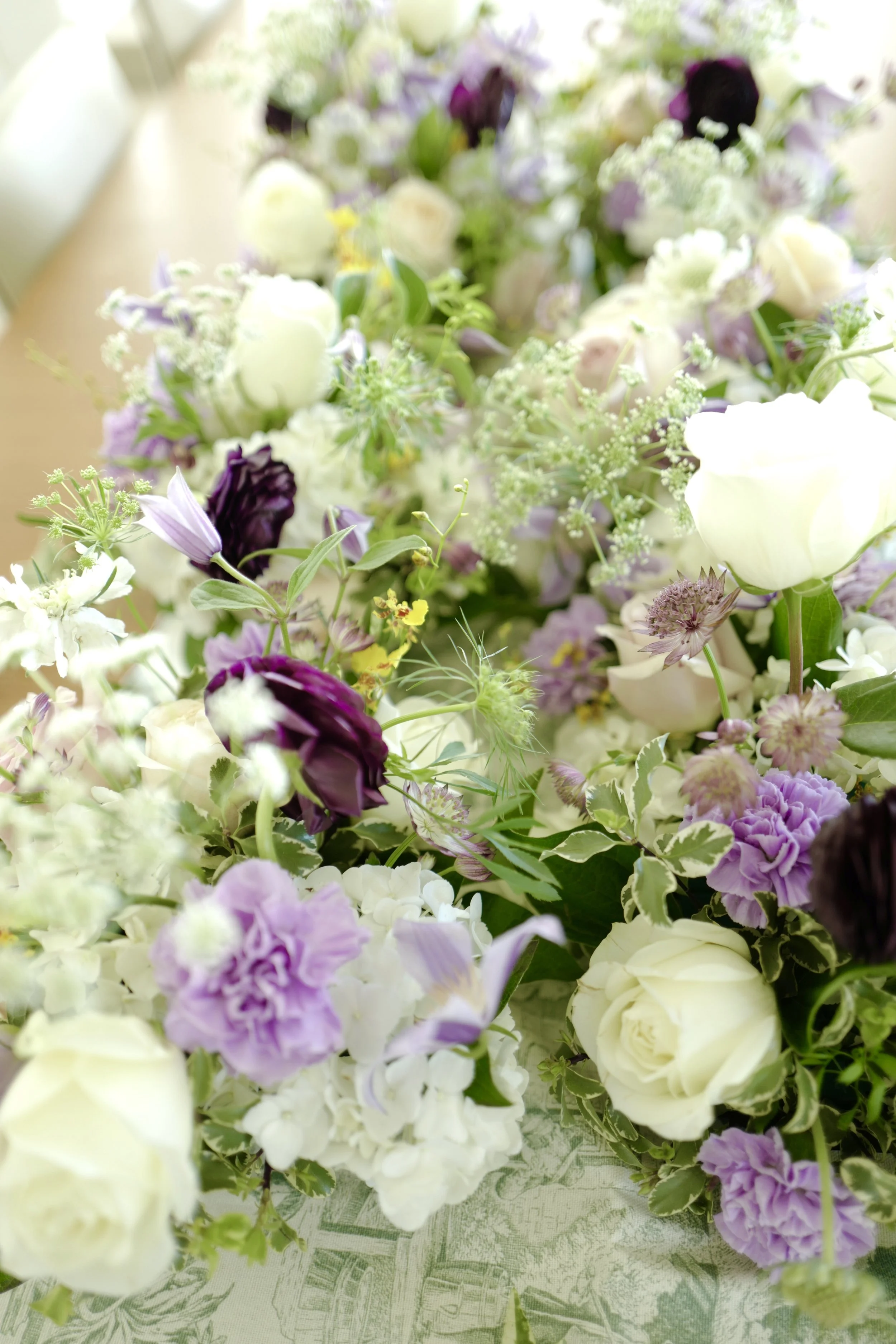 A floral arrangement with white, purple, and violet flowers on a table.