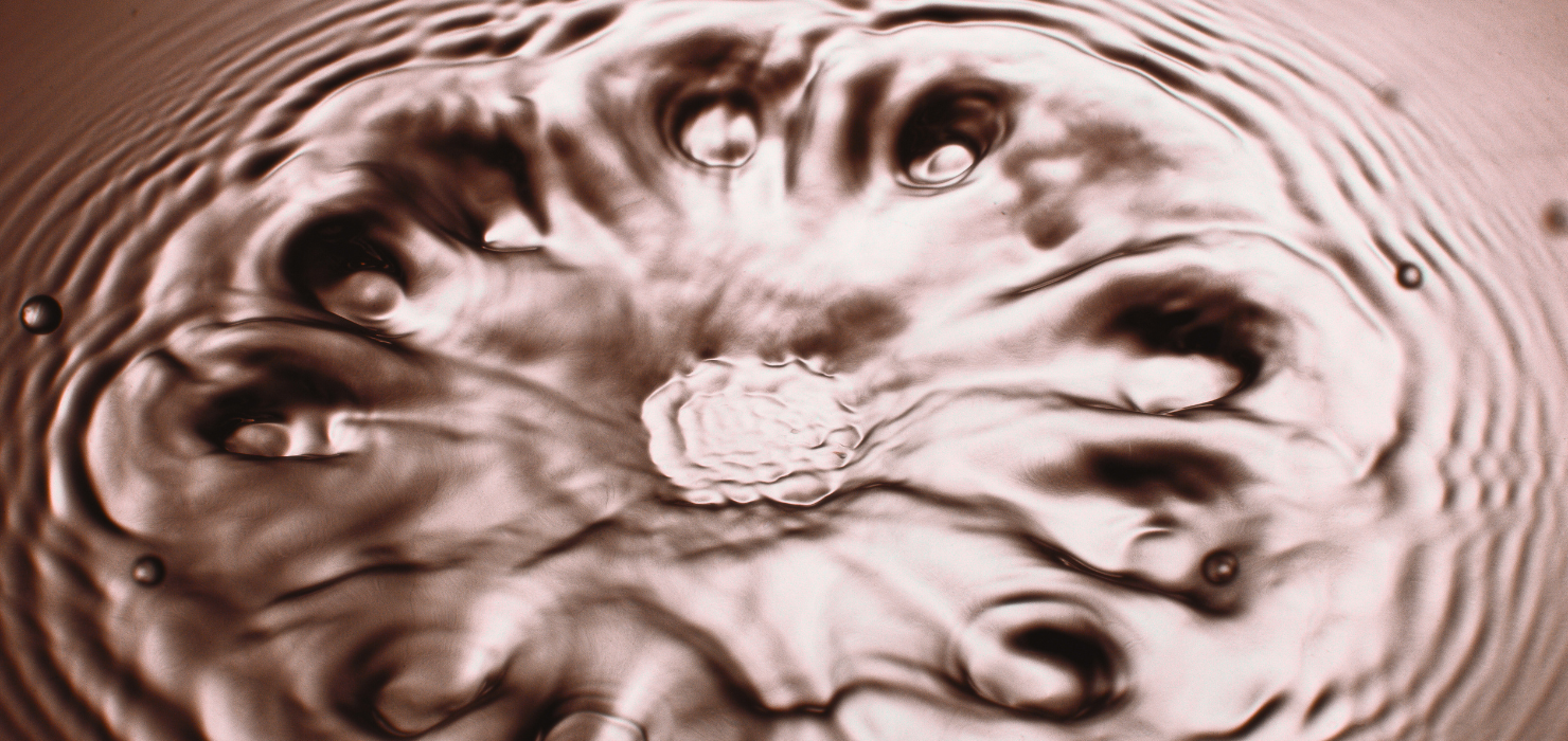Close-up of rippling water surface with concentric circles and swirling patterns.