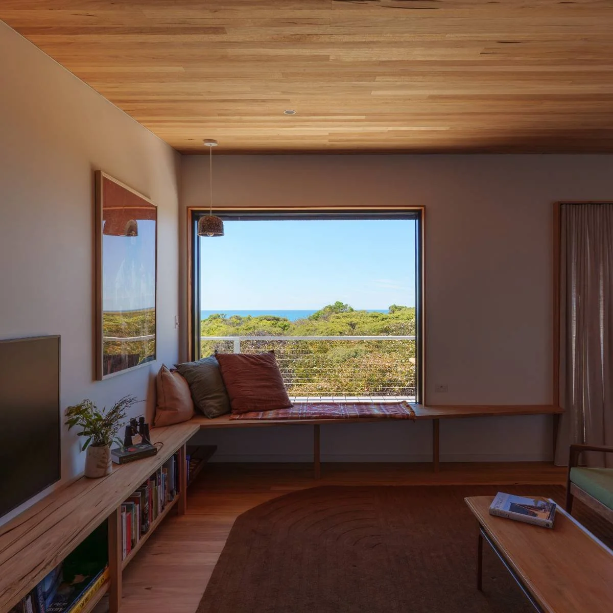 Modern kitchen with a sliding glass door leading to a balcony overlooking greenery and blue sky, with a table and chairs outside.