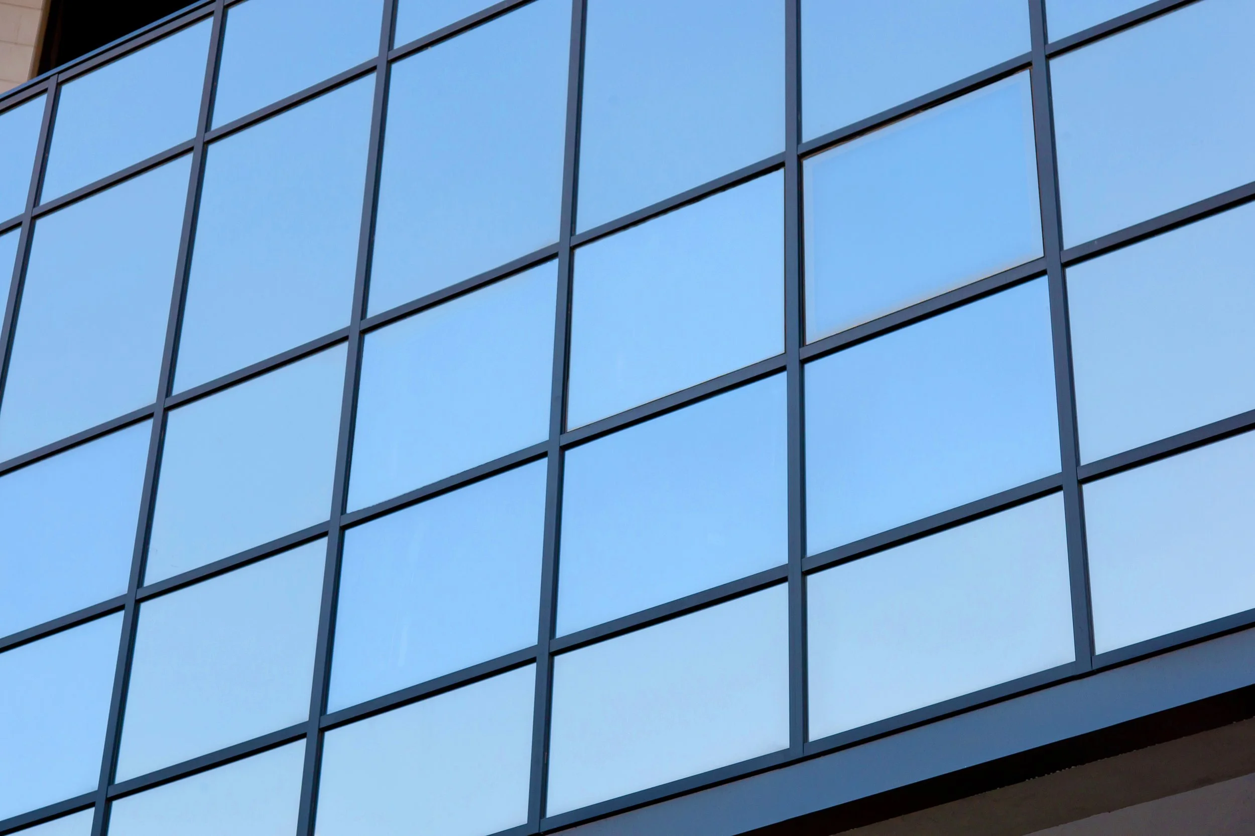 Reflective window film on modern glass facade providing daytime privacy and solar heat reduction