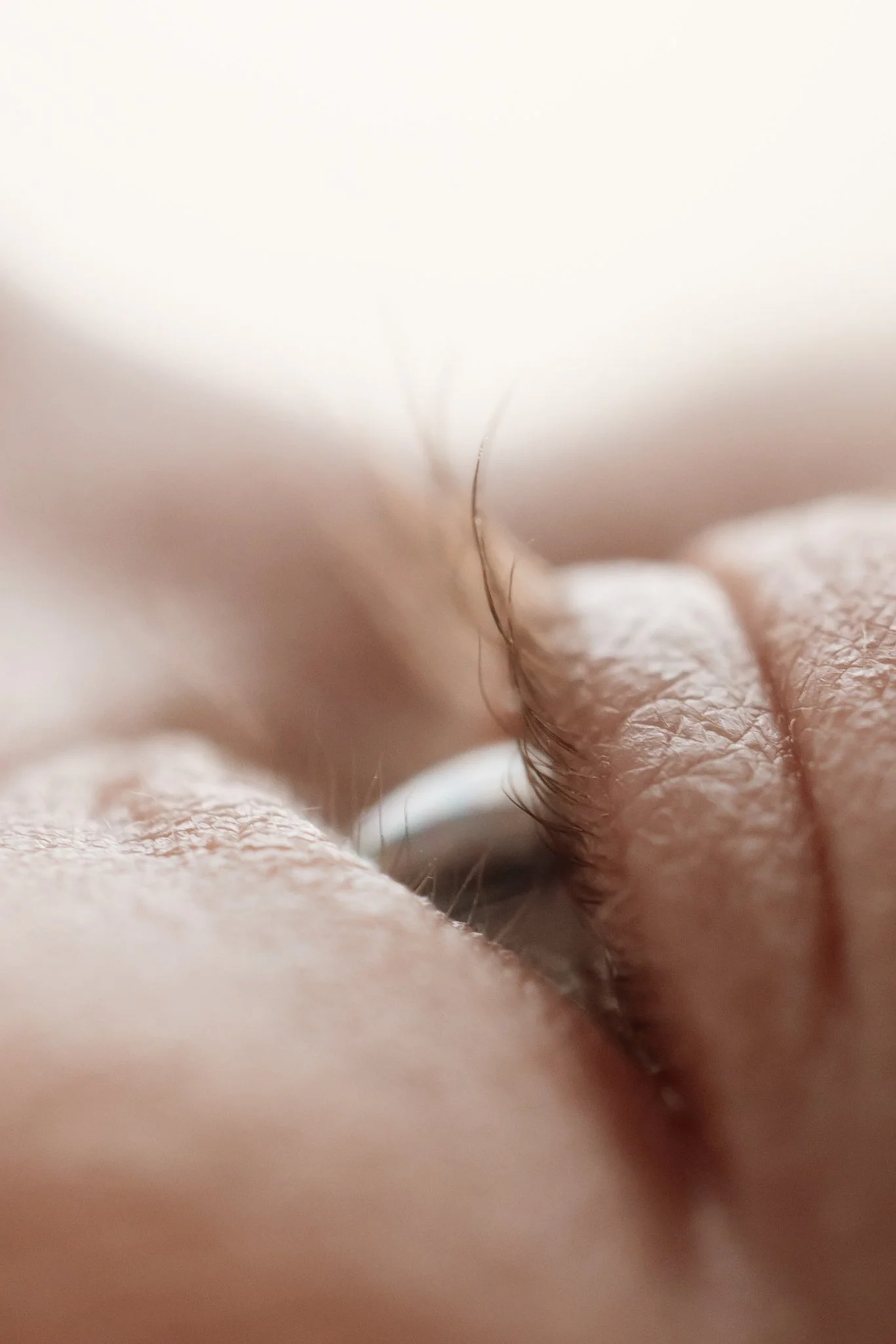 Close-up of a baby's eyes, taken in macro settings, showing skin texture and fine facial hair.