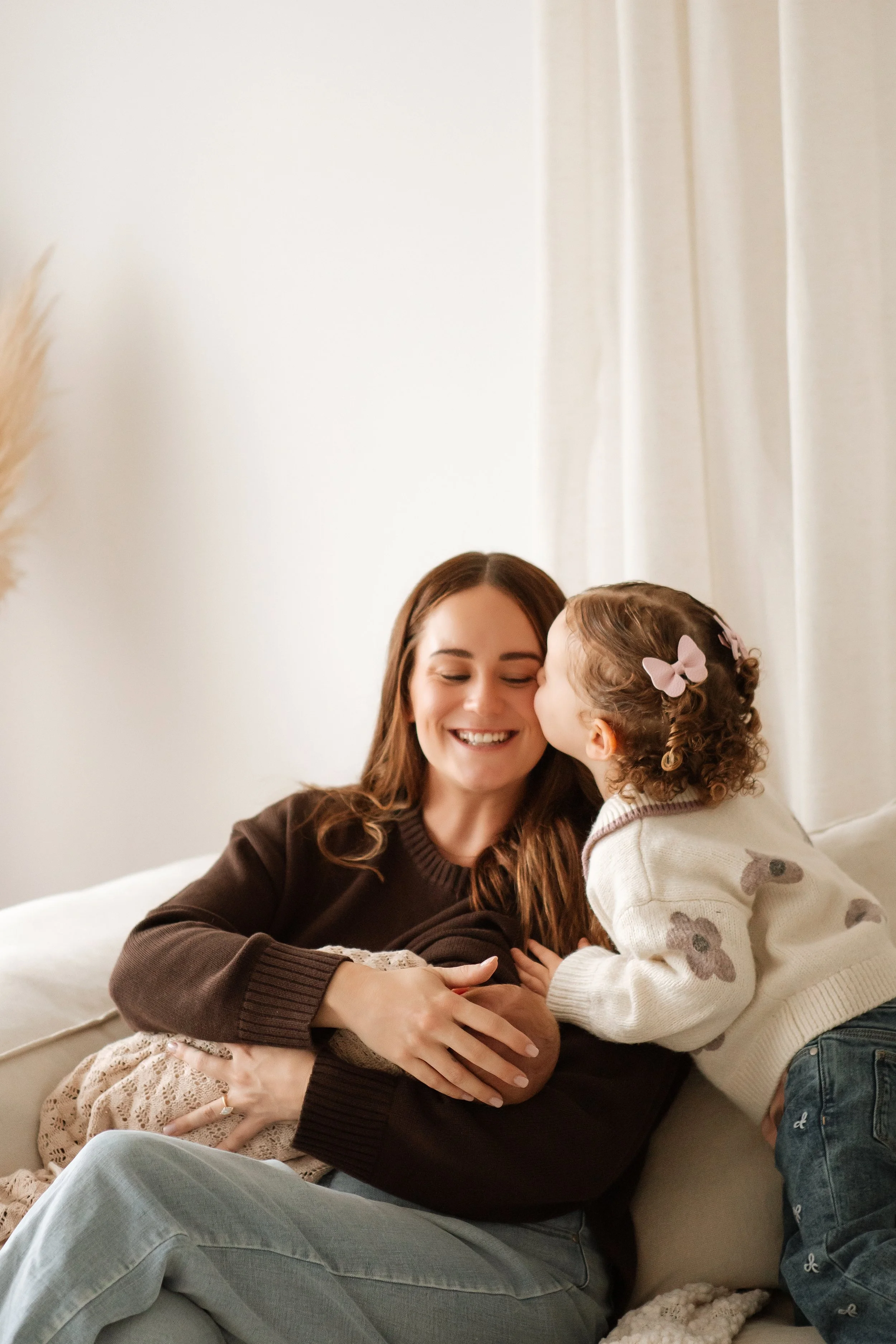 A woman and a young girl sharing a tender moment, with the girl kissing the woman on the cheek.