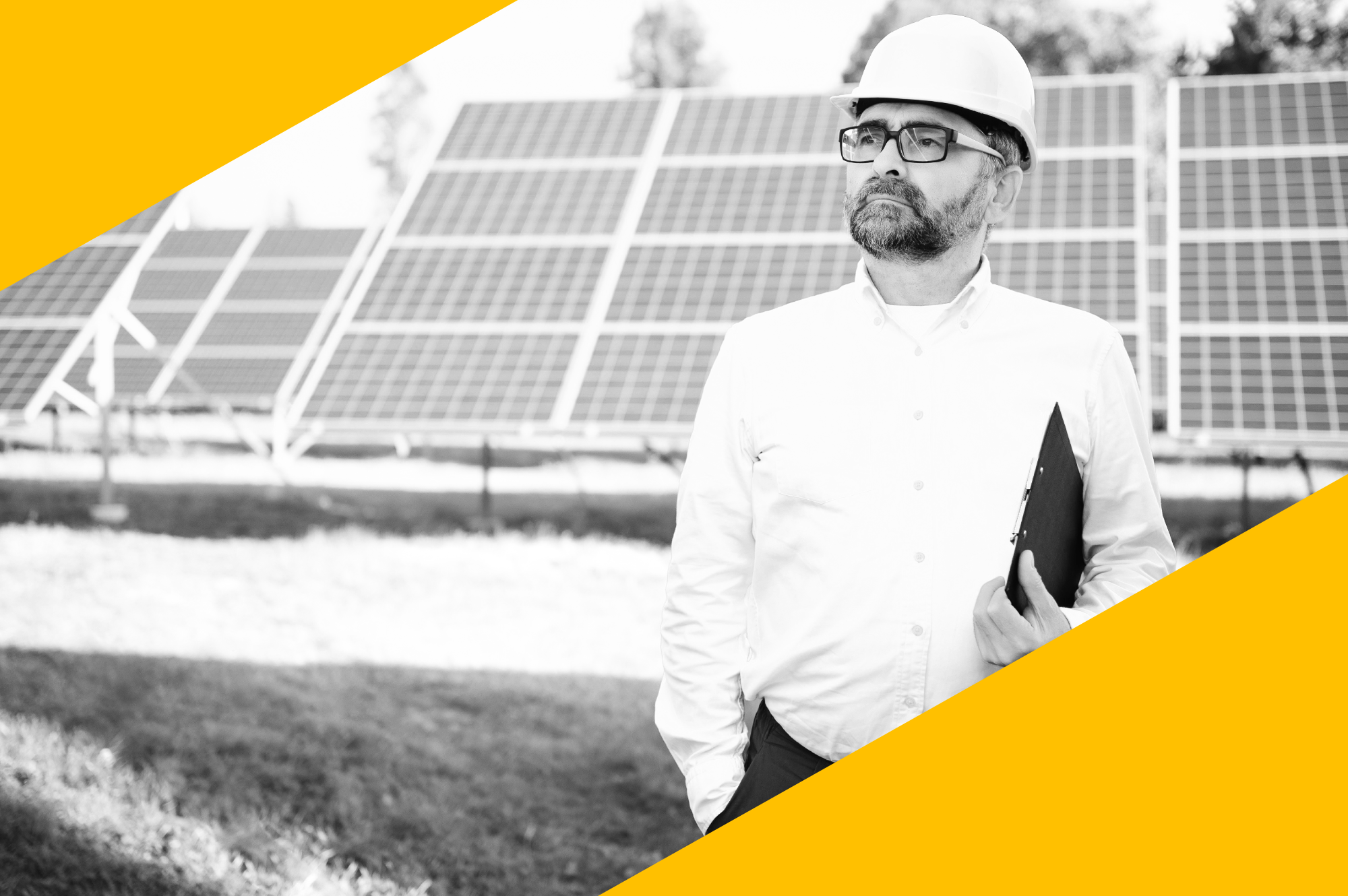 Ein Mann in weißem Hemd und Schutzhelm steht vor Solarzellen auf einer Freifläche und hält eine schwarze Aktenmappe.