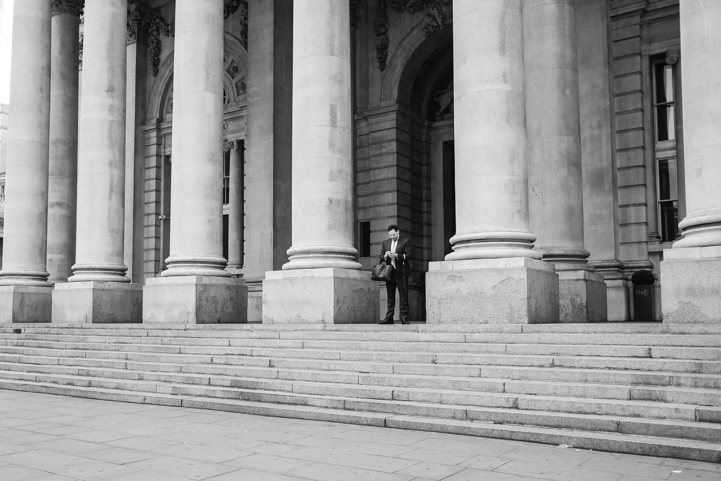 a man in a suite in front of a public building with pillars