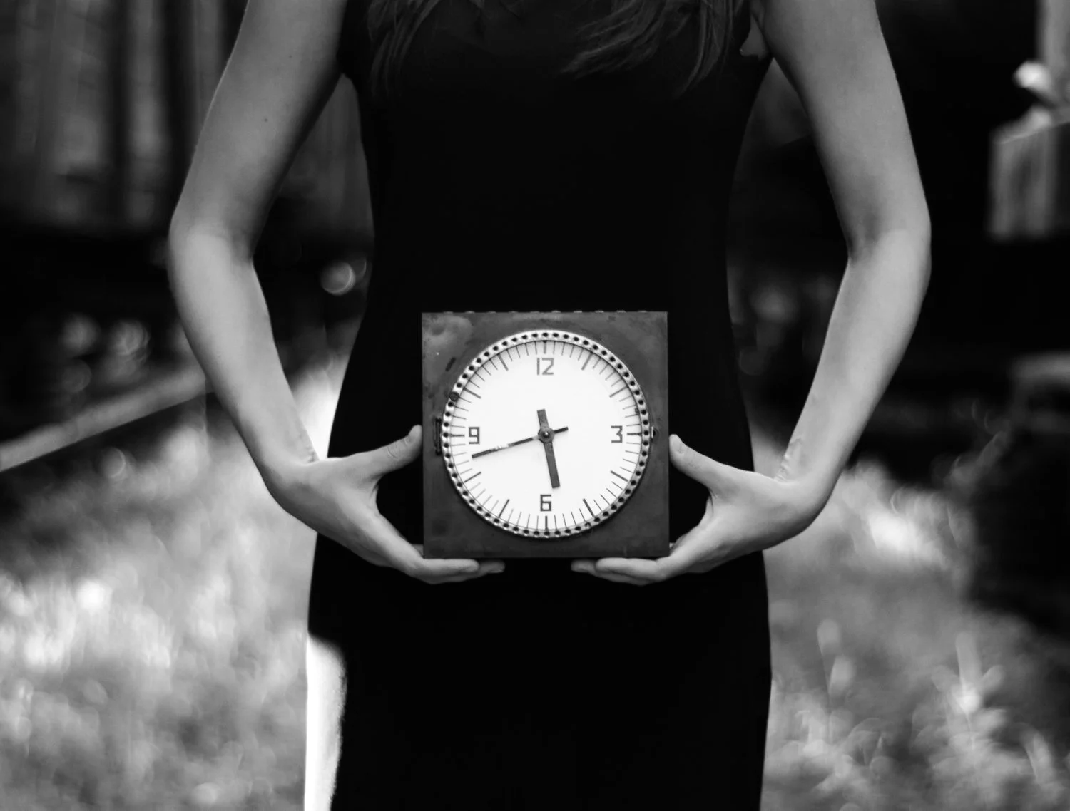 a woman in a black dress holding a clock