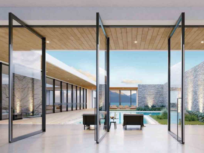 Modern house with large glass doors opening to outdoor patio and pool area, with lounge chairs and stone walls