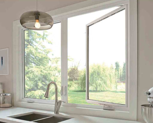 Kitchen window overlooking green trees and a lawn with a modern faucet and a stand mixer on the counter.