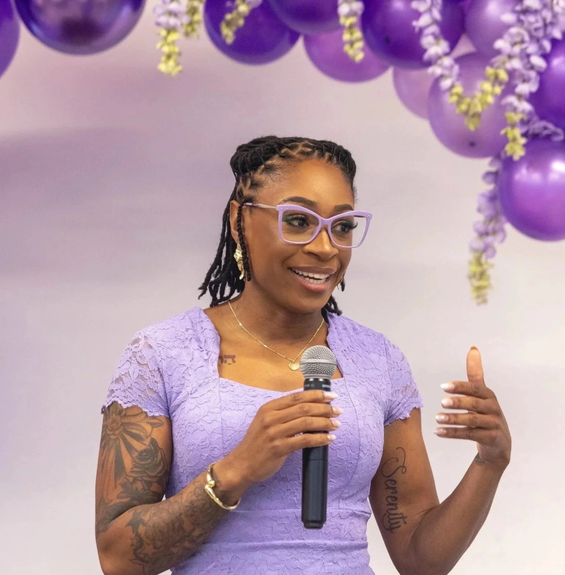 Rashida Saunders speaking into a microphone at a community storytelling event.