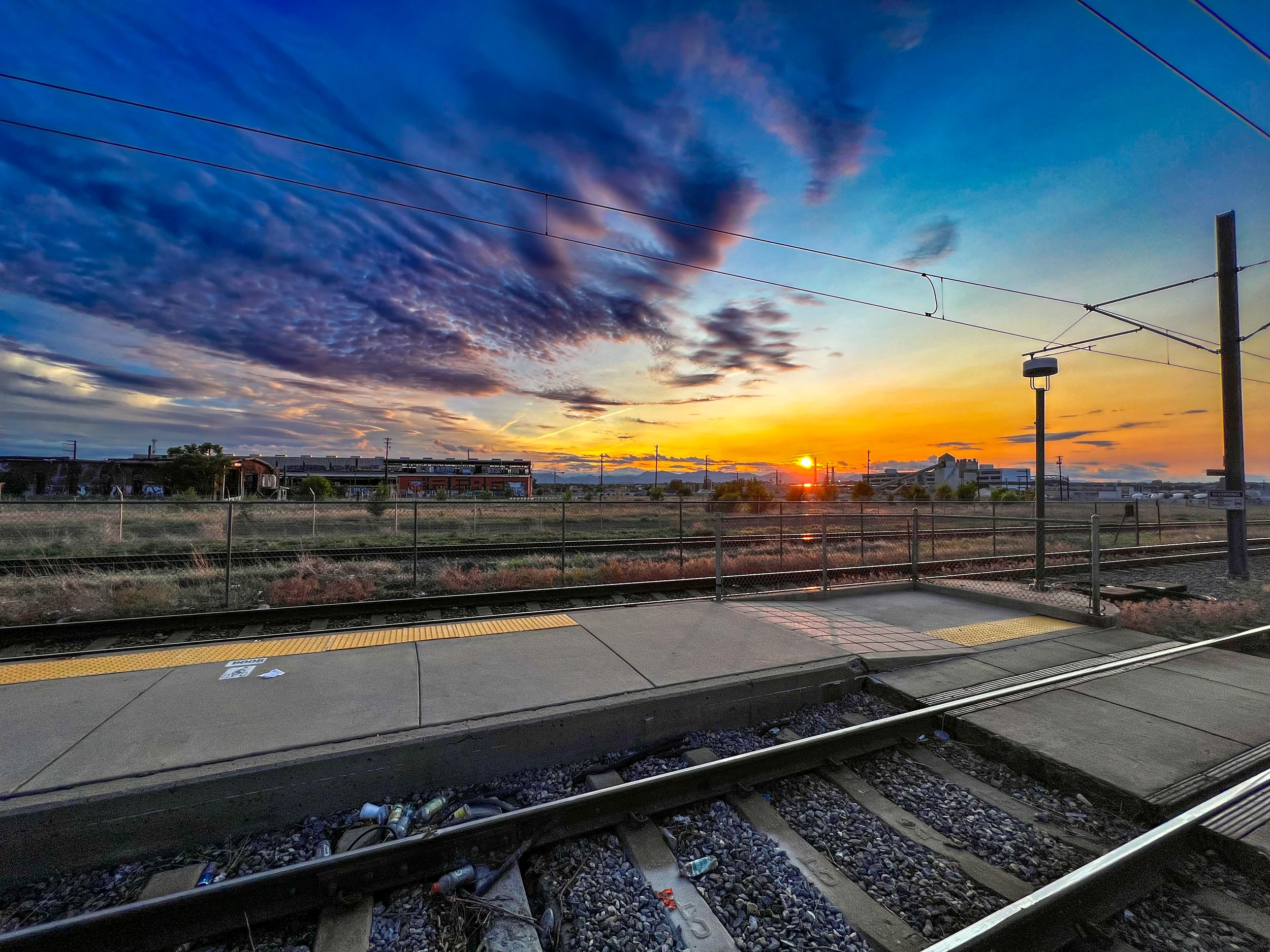 View of train tracks at sunset with colorful sky and clouds