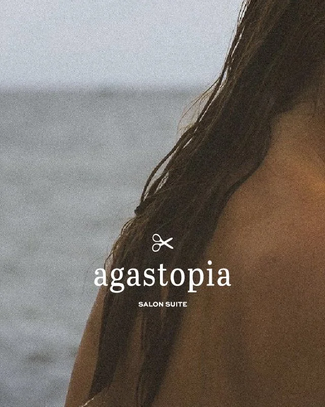 Close-up of a woman's hair and shoulder with ocean background, text overlay reads 'agastopia SALON SUITE' with a scissors icon.