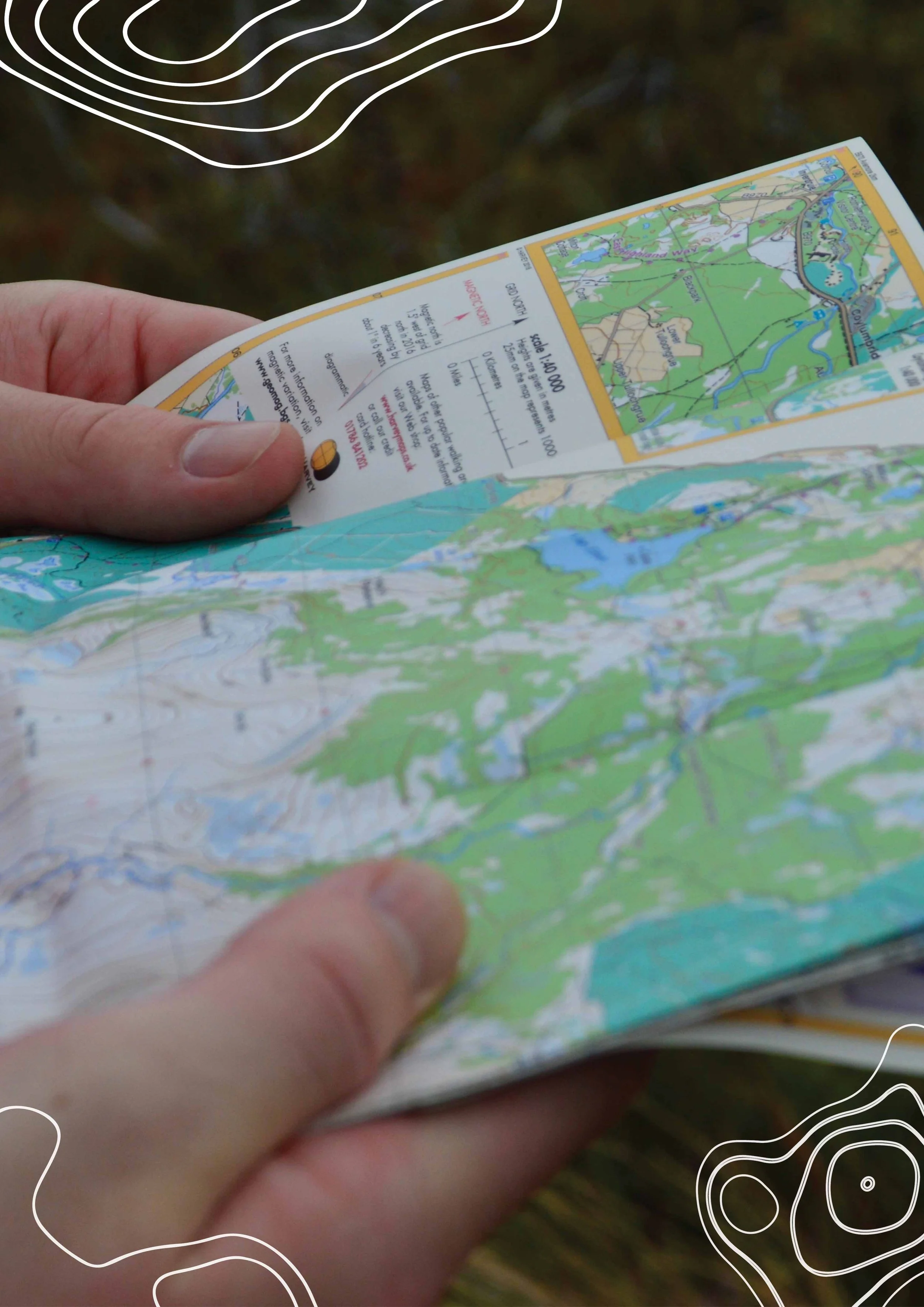 A person holding an open topographic map outdoors, with a landscape background.