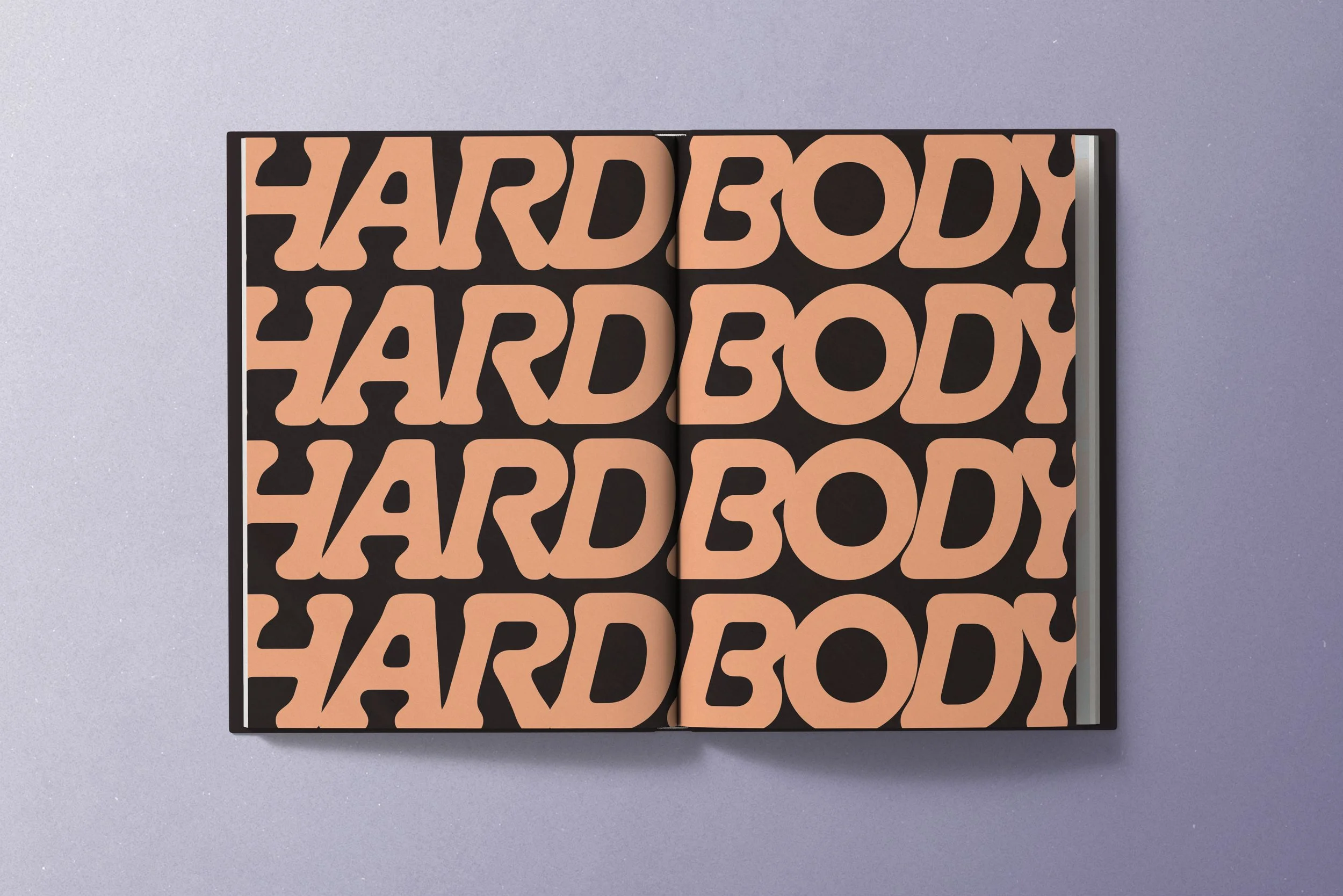 Open book with repeated bold text 'HARD BODY' in peach and black print on a gray background.