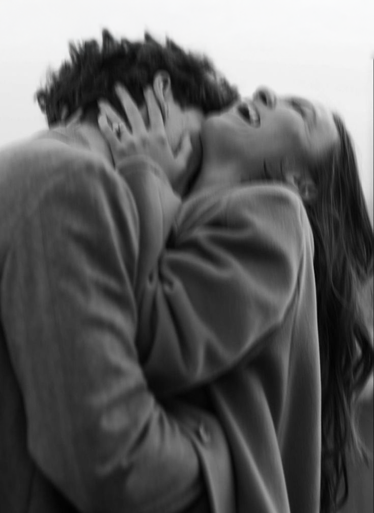 A black-and-white photo of a couple kissing, with the person on the left holding the face of the person on the right.