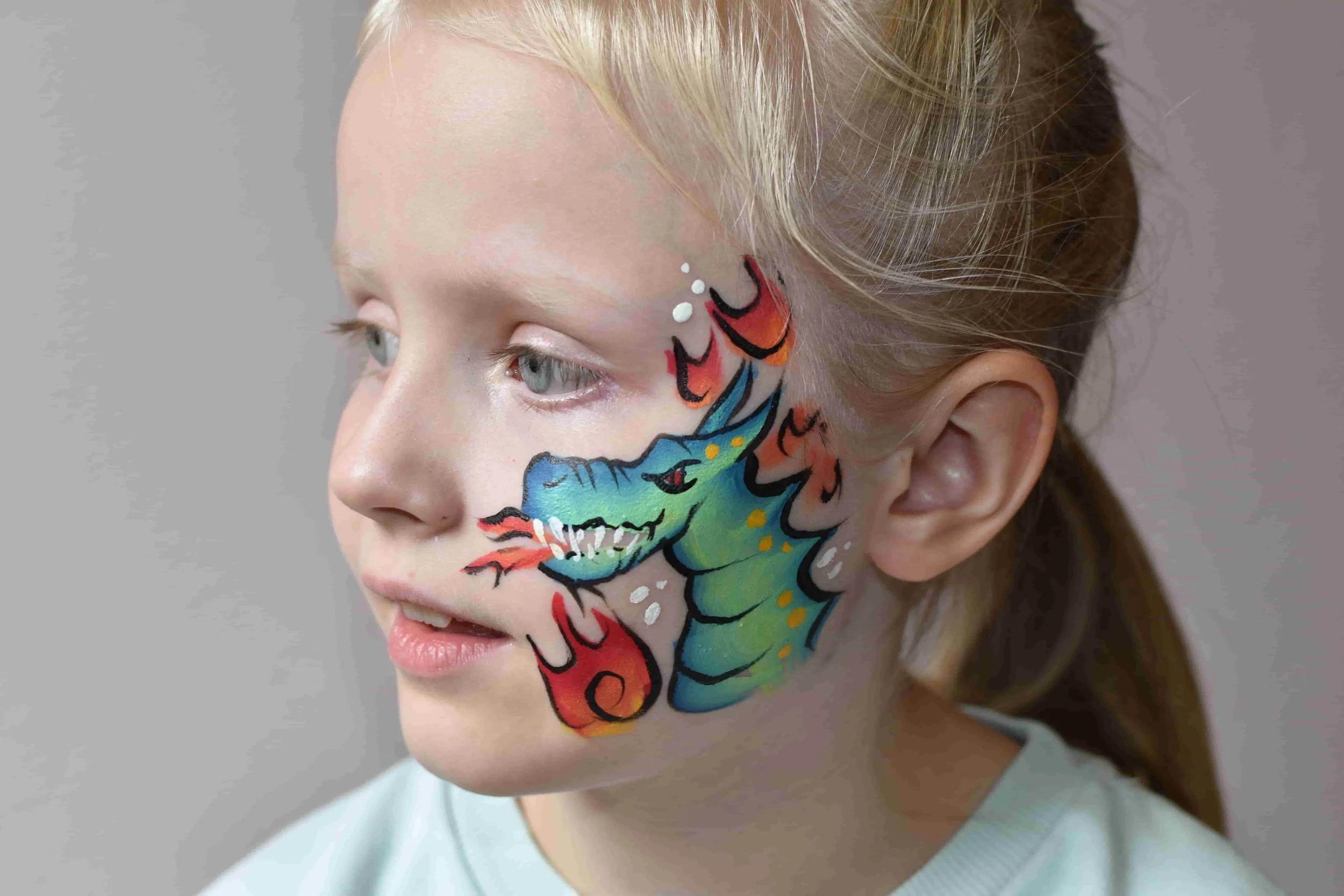 Lasten kasvomaalaus tulta syöksevä lohikäärme poskessa