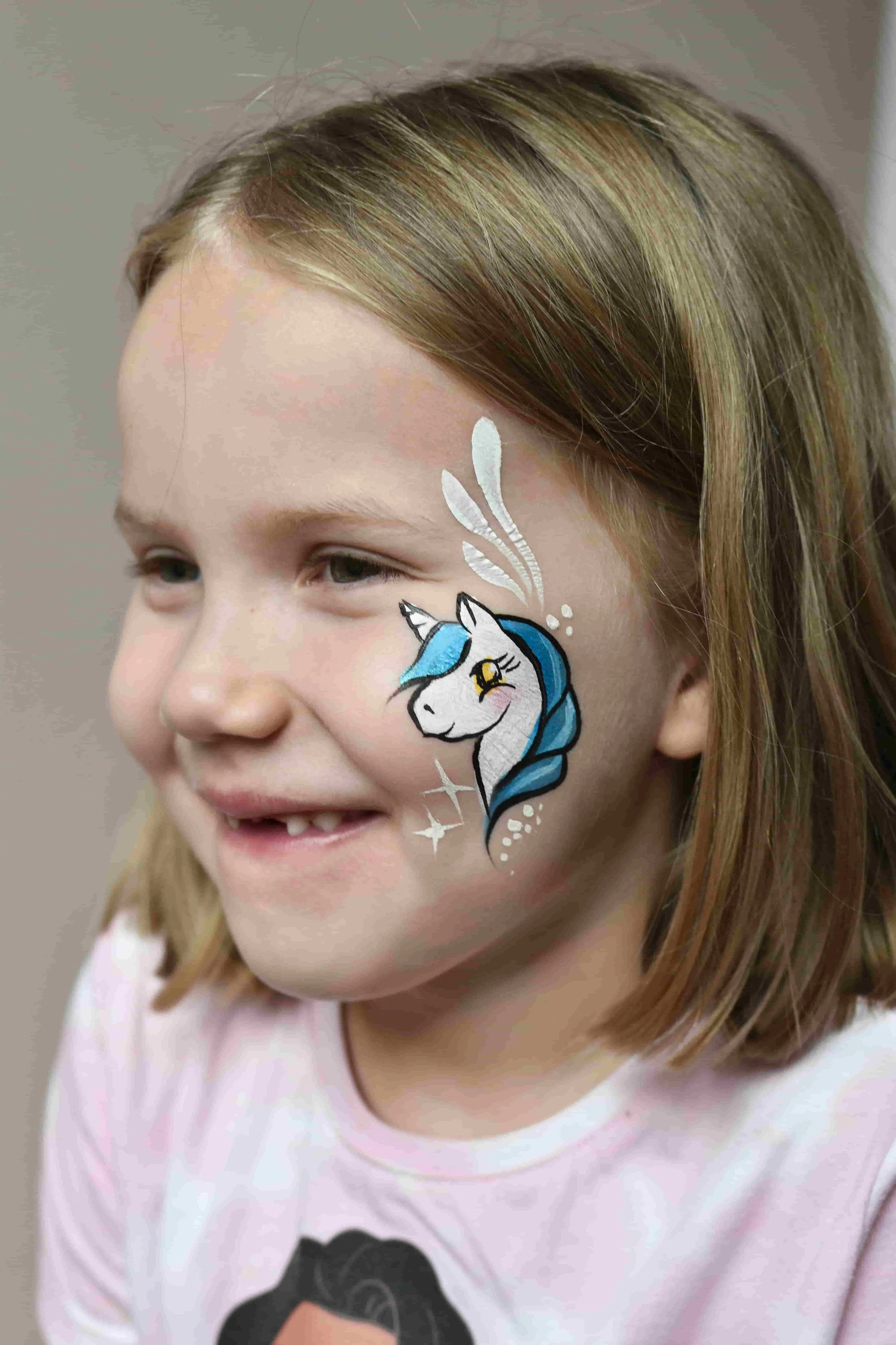 Yksisarvinen sinisellä harjalla lapsen poskessa