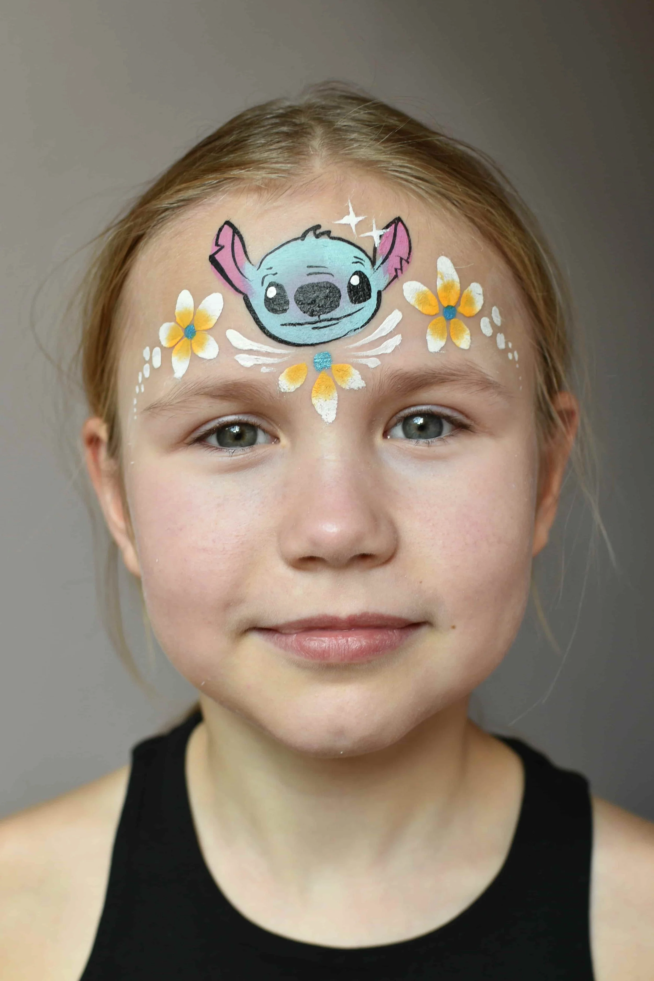 Stitch kasvomaalaus otsalla ja kukkia koristeena