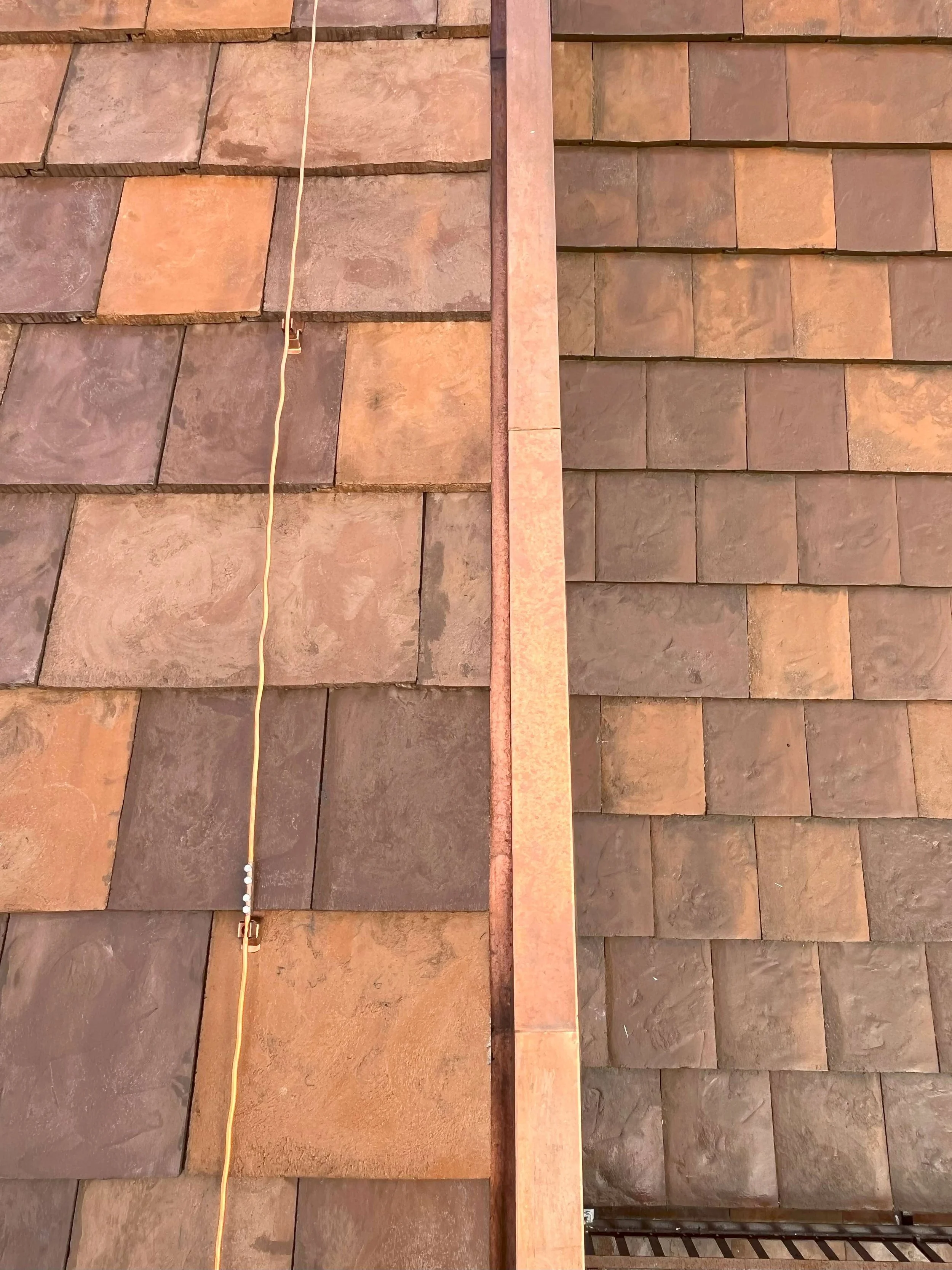 Ansicht einer Dachschindel mit Kabel und Metallstreifen, die als Teil der Dachinstallation dienen.