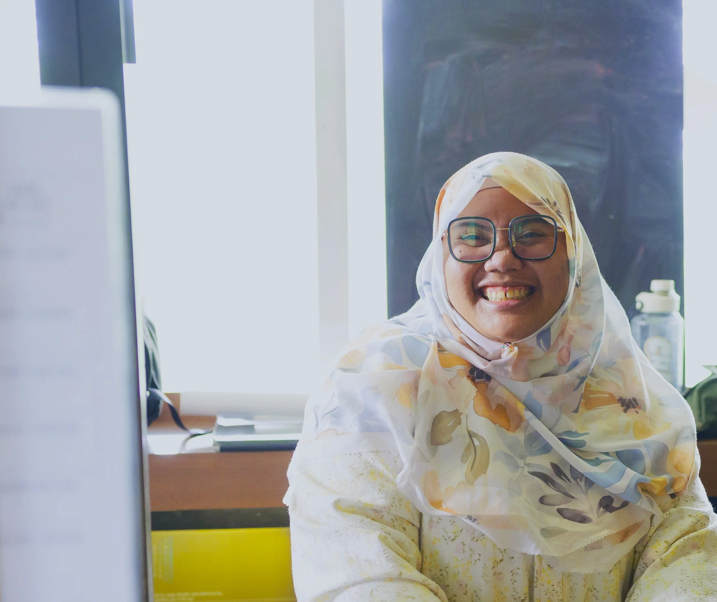 Young woman with a floral hijab and square glasses smiling
