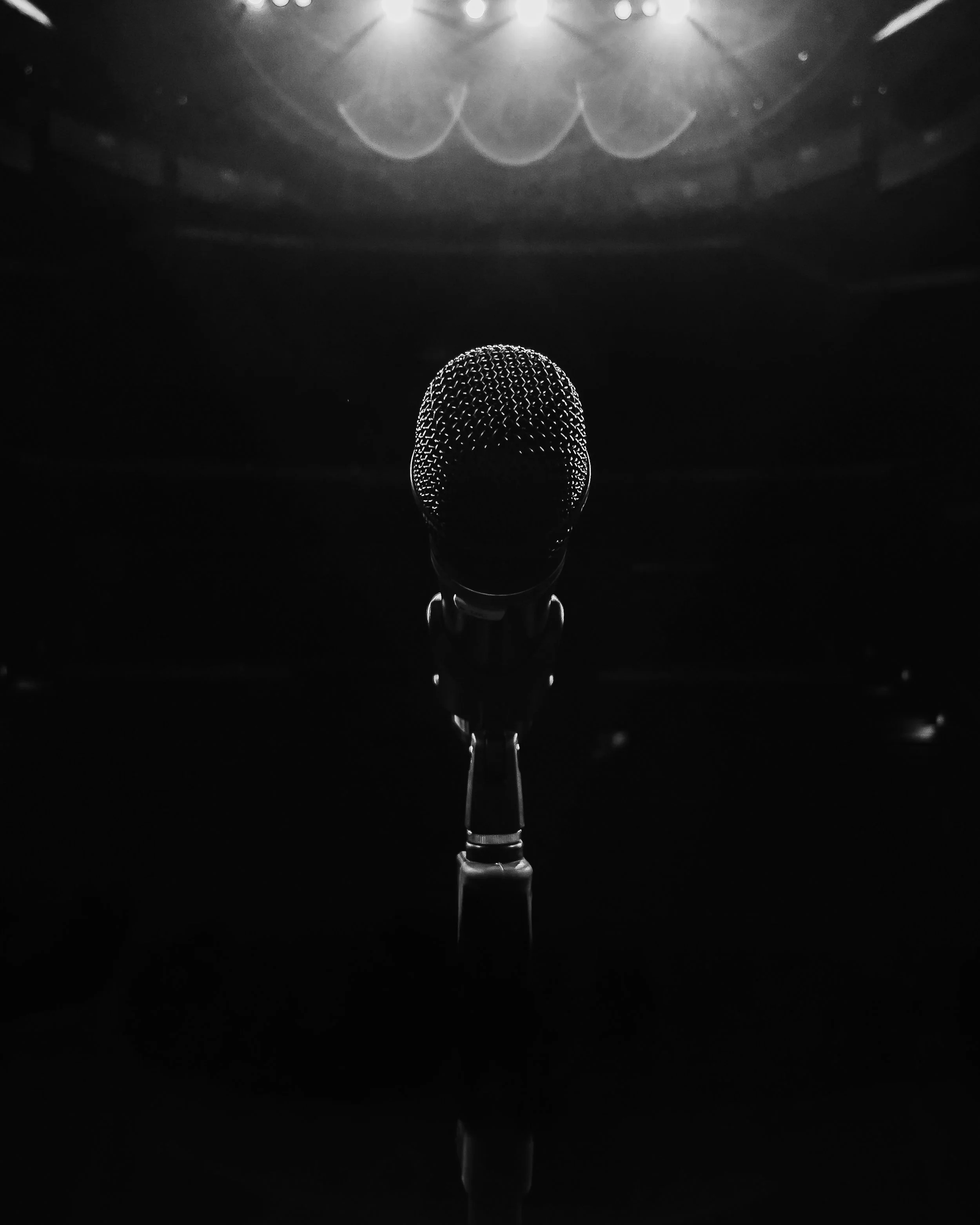 A black and white image of a microphone on stage
