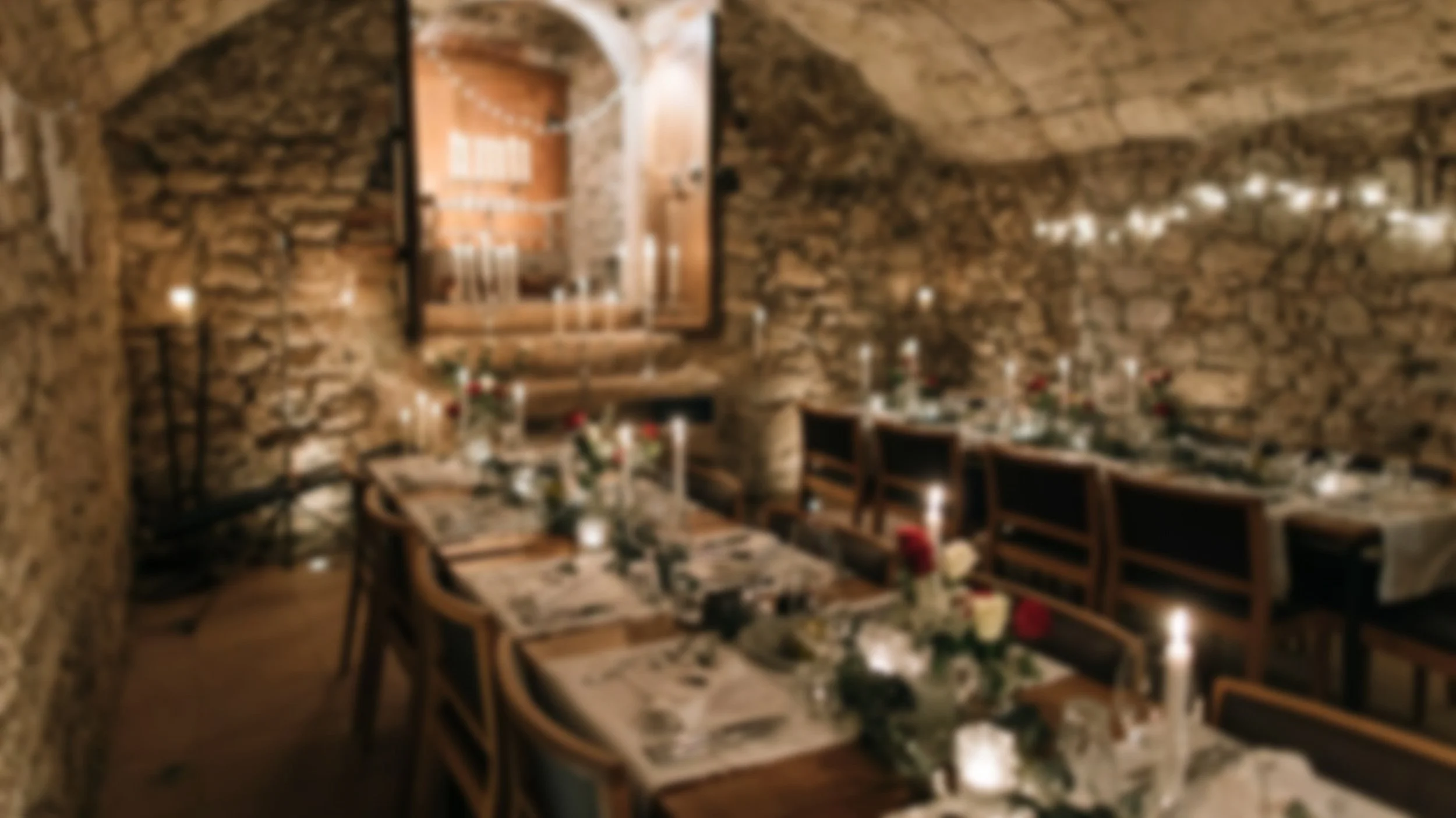 Ein gemütlicher Speiseraum mit steinernen Wänden, festlich gedeckten Tischen, Kerzen und Blumen für eine Feier oder ein festliches Ereignis.