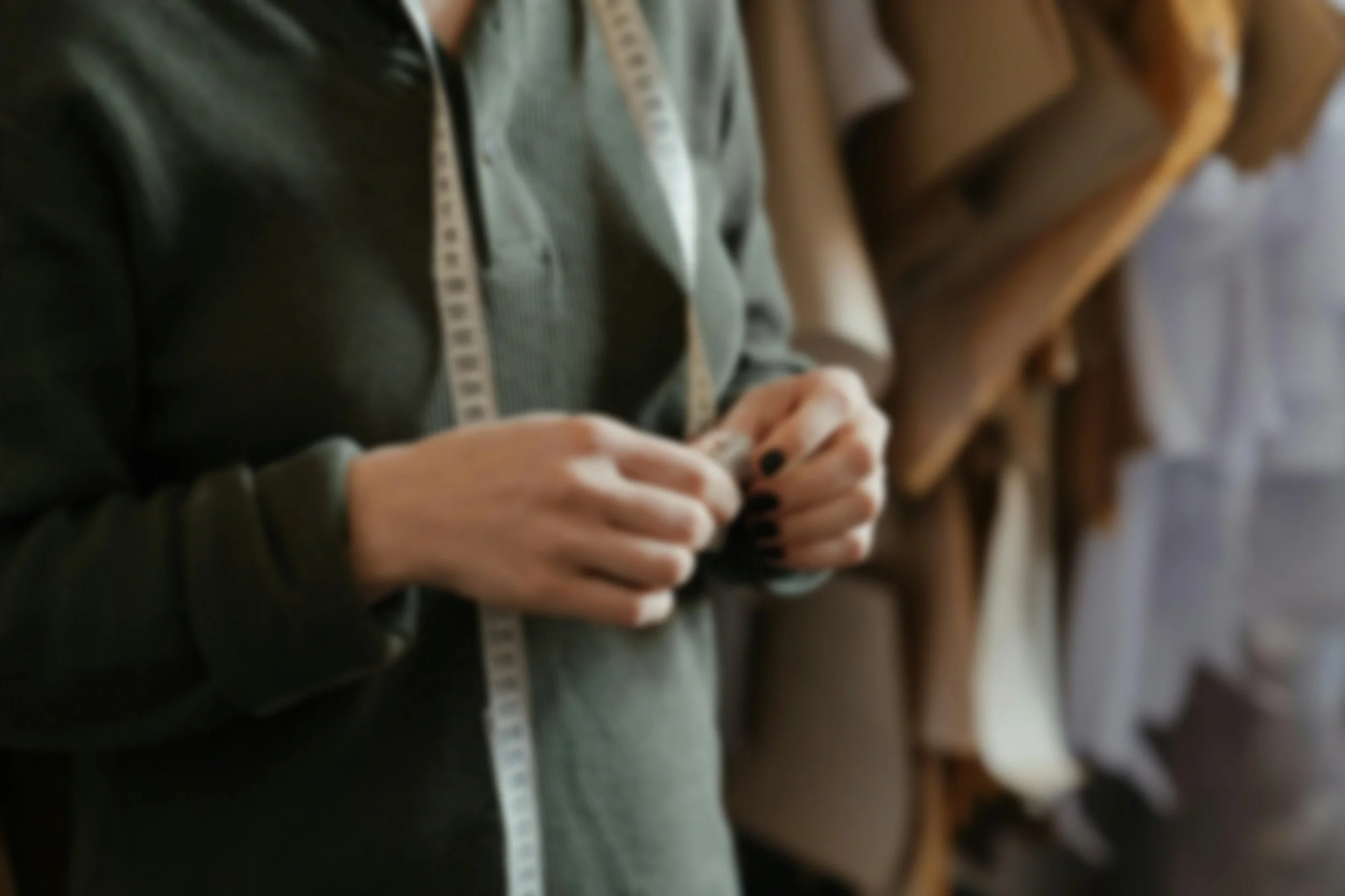 Person mit dunklen Nägeln, die eine Nähmaschine bedient.