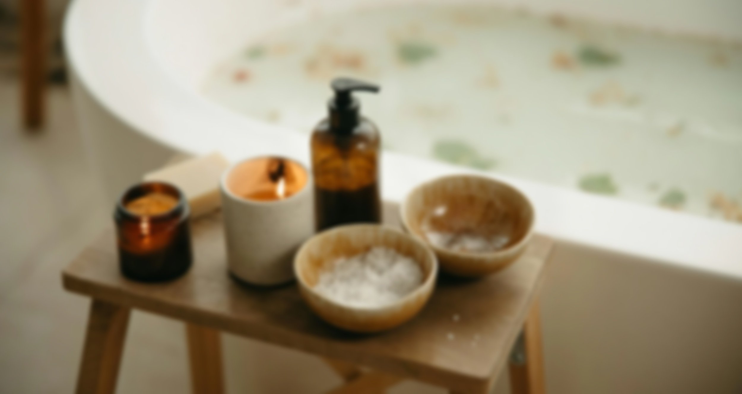 Nächstisch mit Kerzen, einem Seifenspender und Schalen, im Hintergrund eine Badewanne