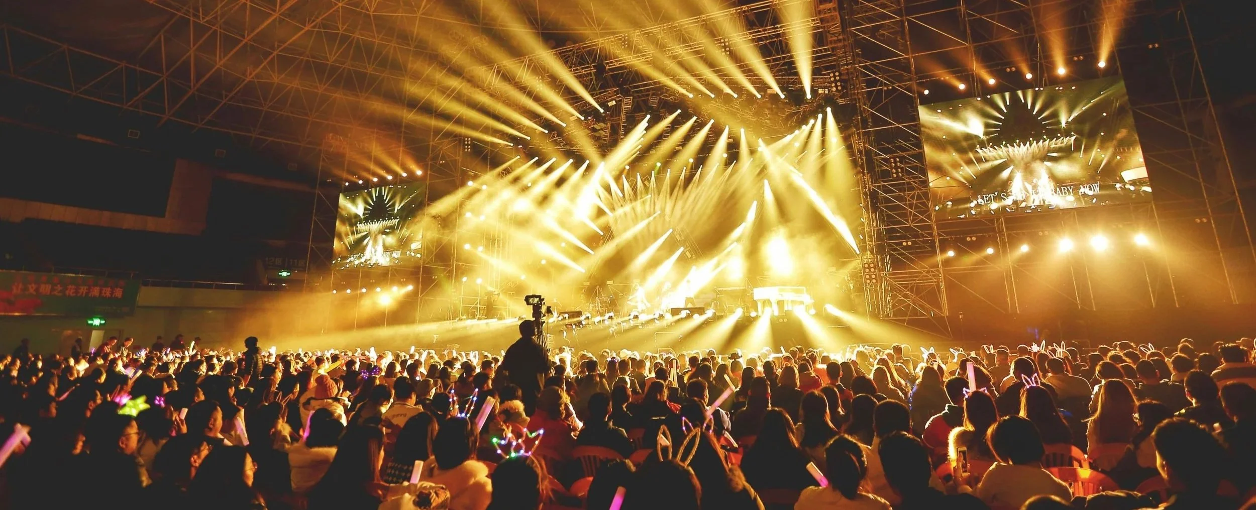 Große Menschenmenge bei einem Konzert mit Bühne, Lichtshow und Publikum mit Bunny-Ohren.