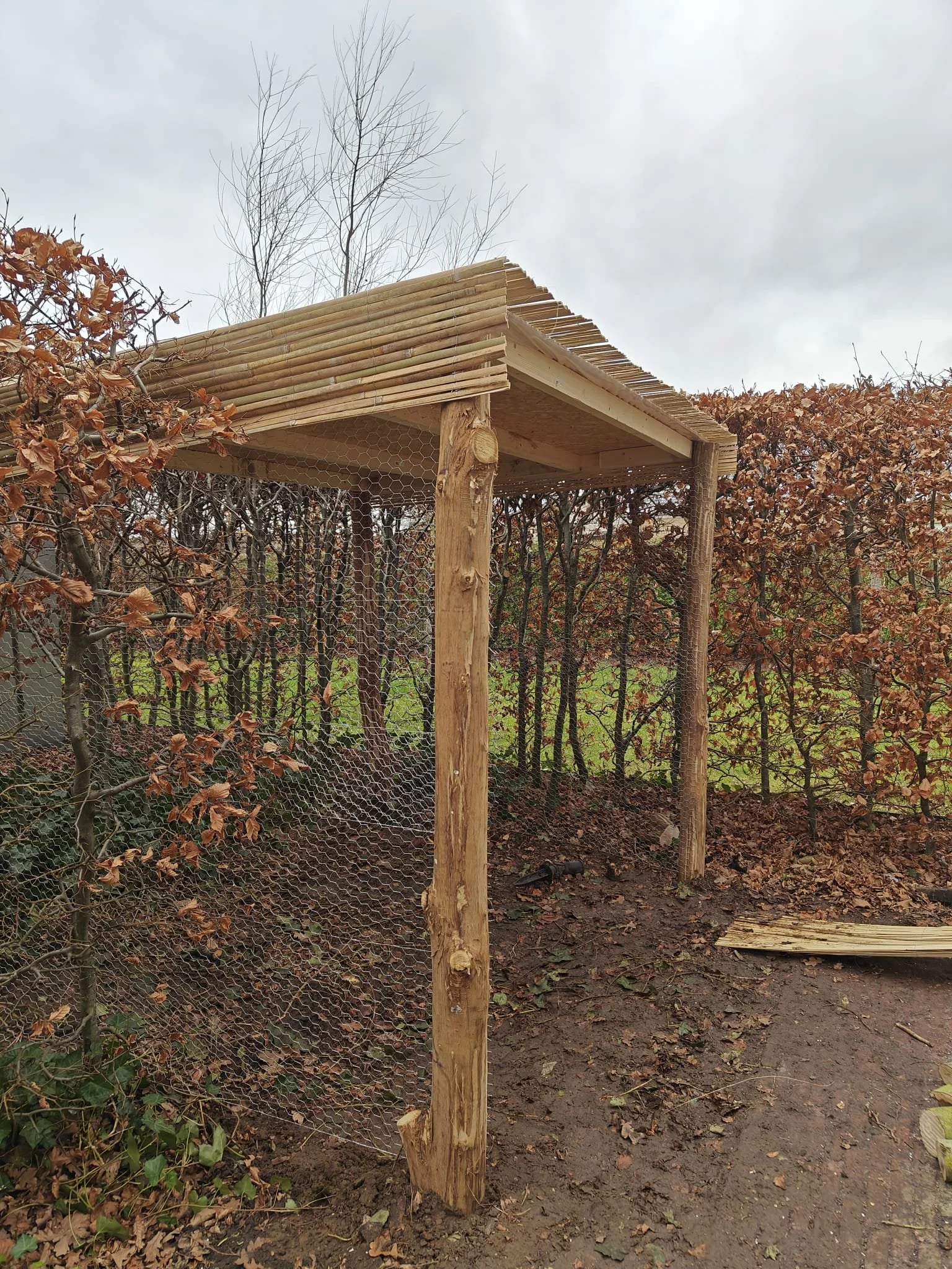 Een houten constructie met een dak waar kachelhout gestockeerd kan worden.