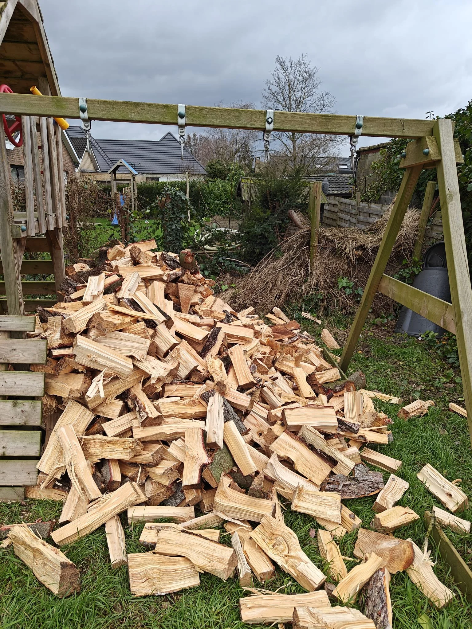 Een grote hoop vers gezaagde houtblokken met een houten schommel.