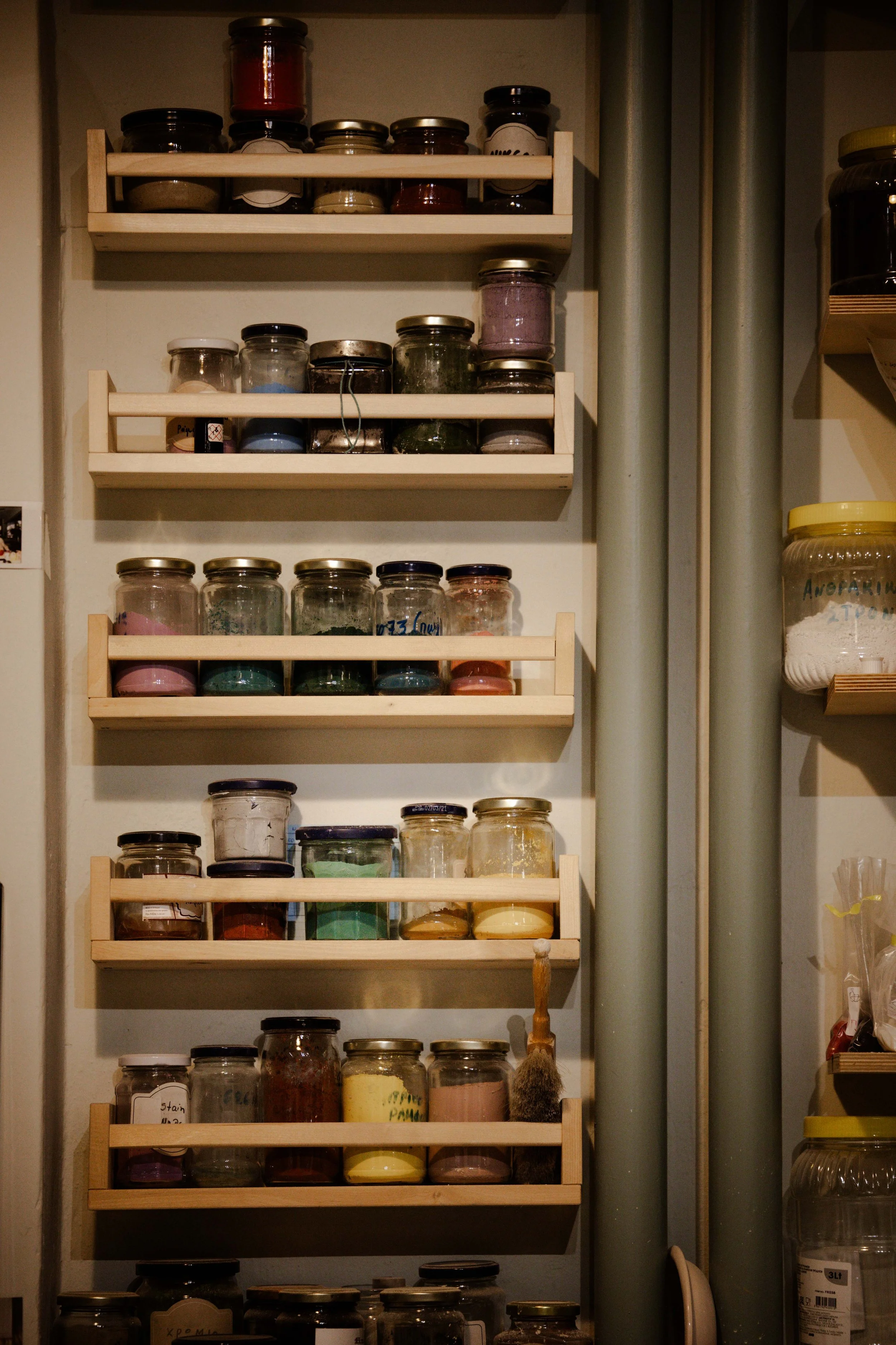 Wall-mounted shelves holding numerous small glass jars filled with powders and herbs, organized in rows.