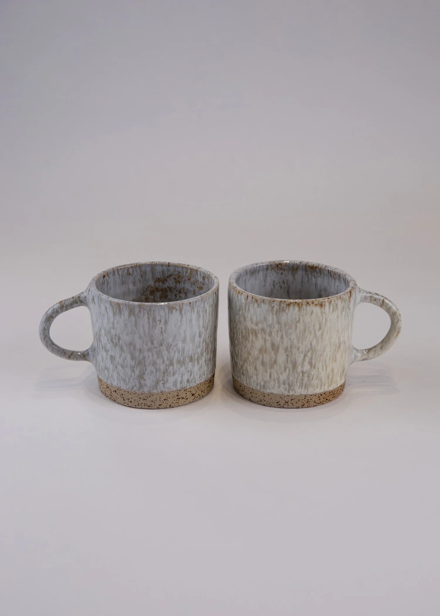 A two-piece cup set crafted from beige-white stoneware clay.