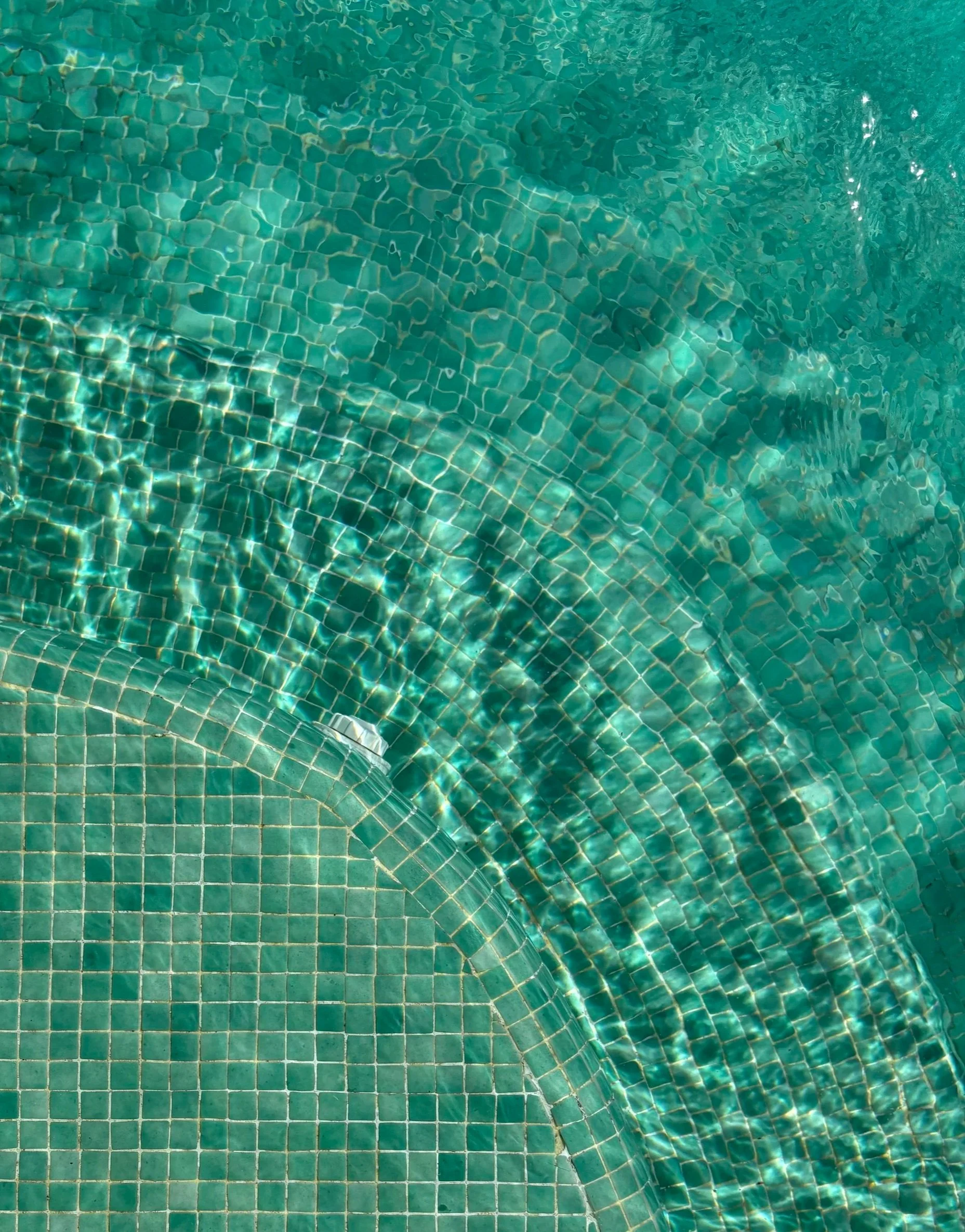 Close-up of a tiled swimming pool with clear turquoise water.