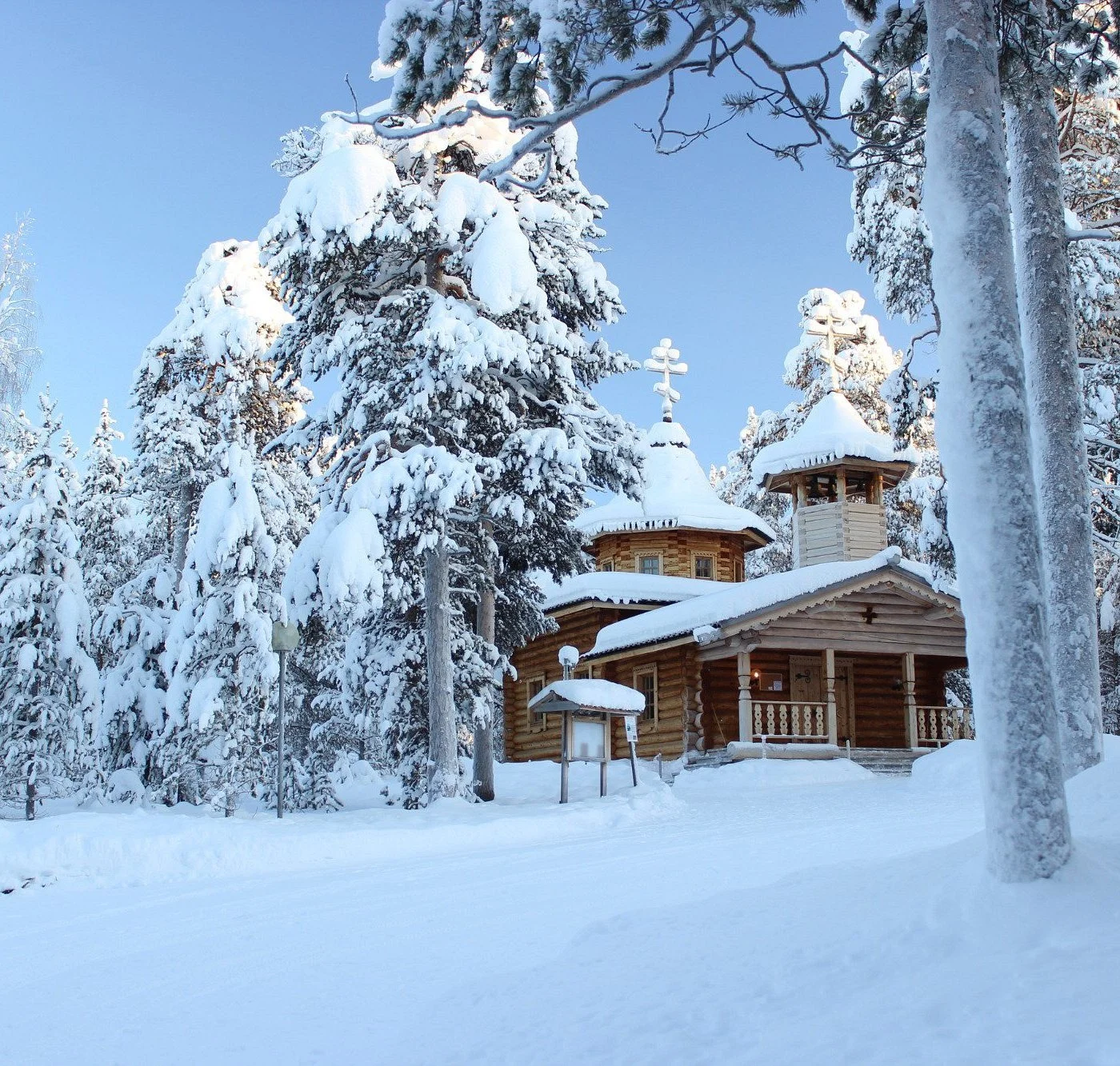 A wooden church surrounded by snow-covered trees in a winter landscape.