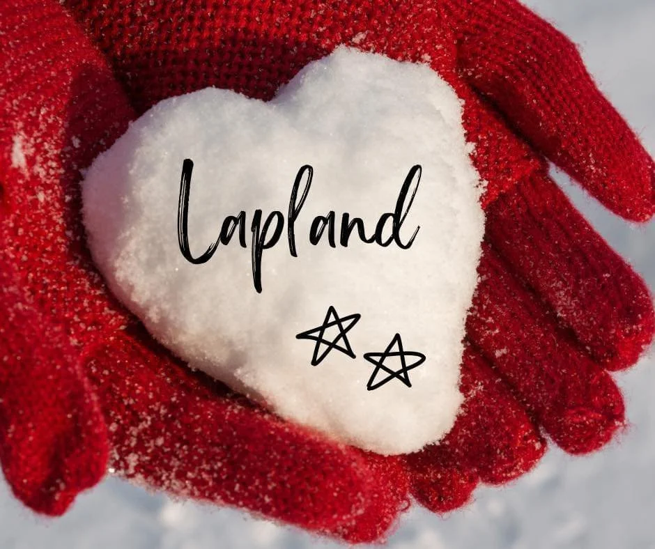 Hands in red gloves holding a heart-shaped piece of snow with the word "Lapland" and two star drawings written on it.