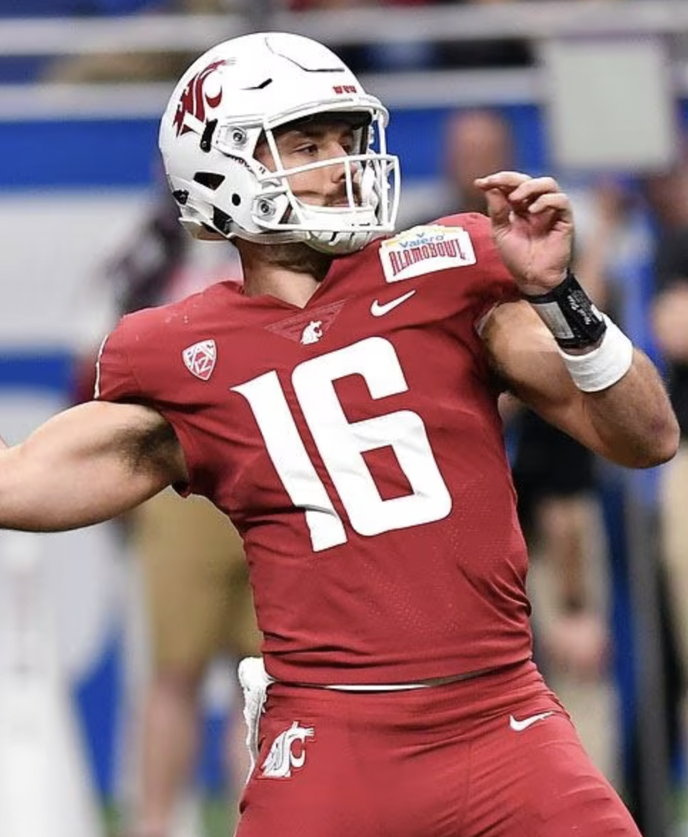 A football player in a red uniform with the number 16, wearing a white helmet with a gray faceguard, celebrates on the field.
