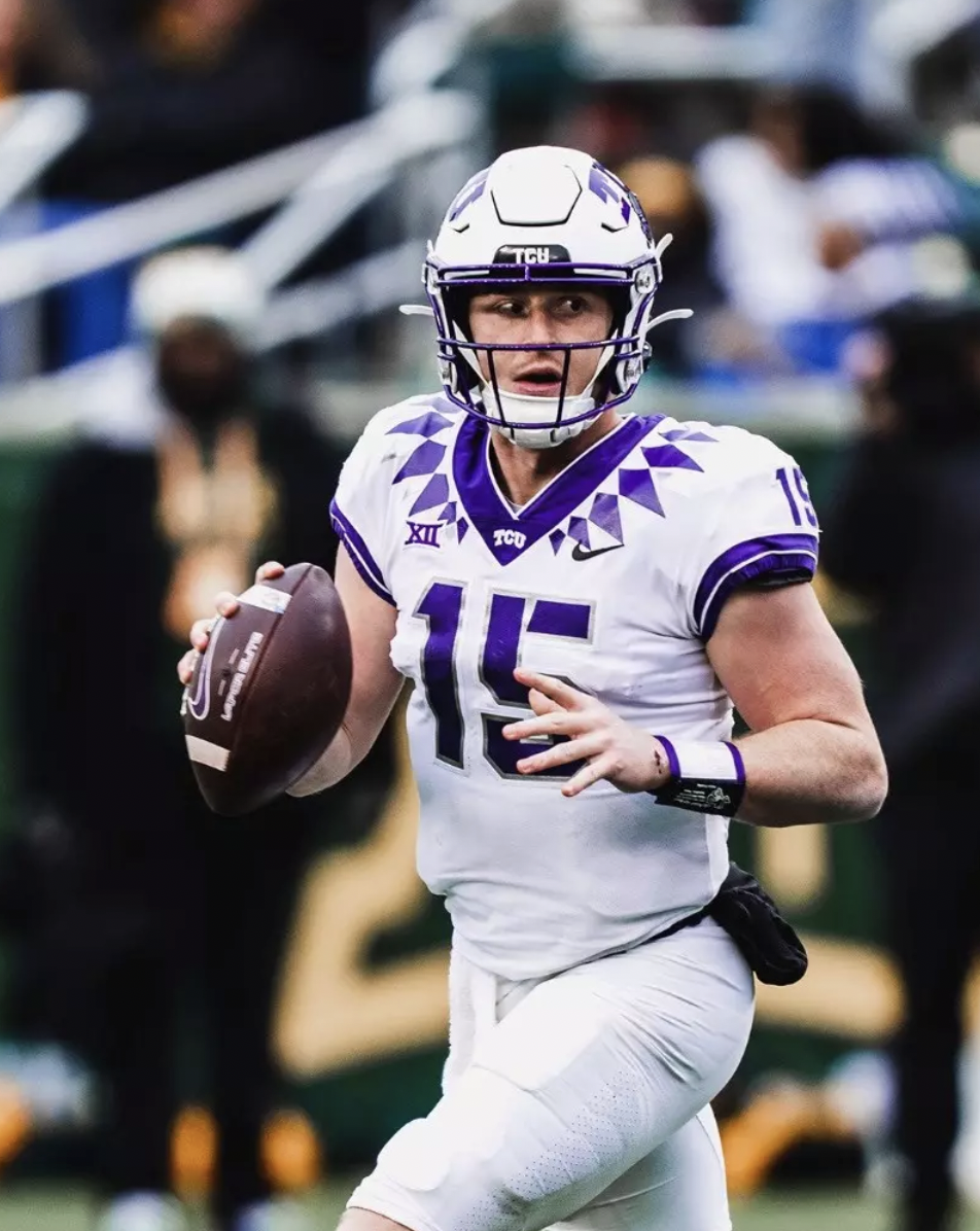 A TCU football player wearing jersey number 15, white uniform with purple accents, holding a football, running on the field during a game.