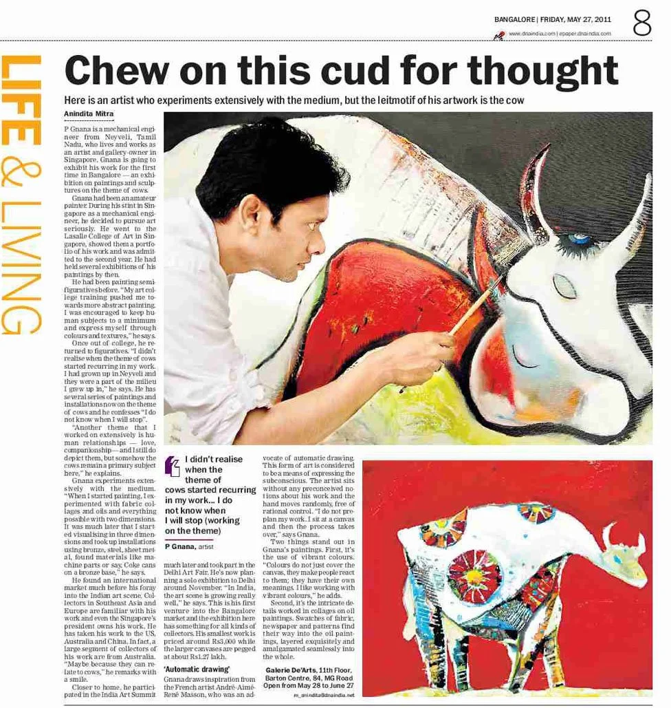 Newspaper article with the headline "Chew on this cud for thought" and a photograph of an artist painting a colorful cow on a large canvas. The artist is a man with dark hair wearing a white shirt, focused on his work.