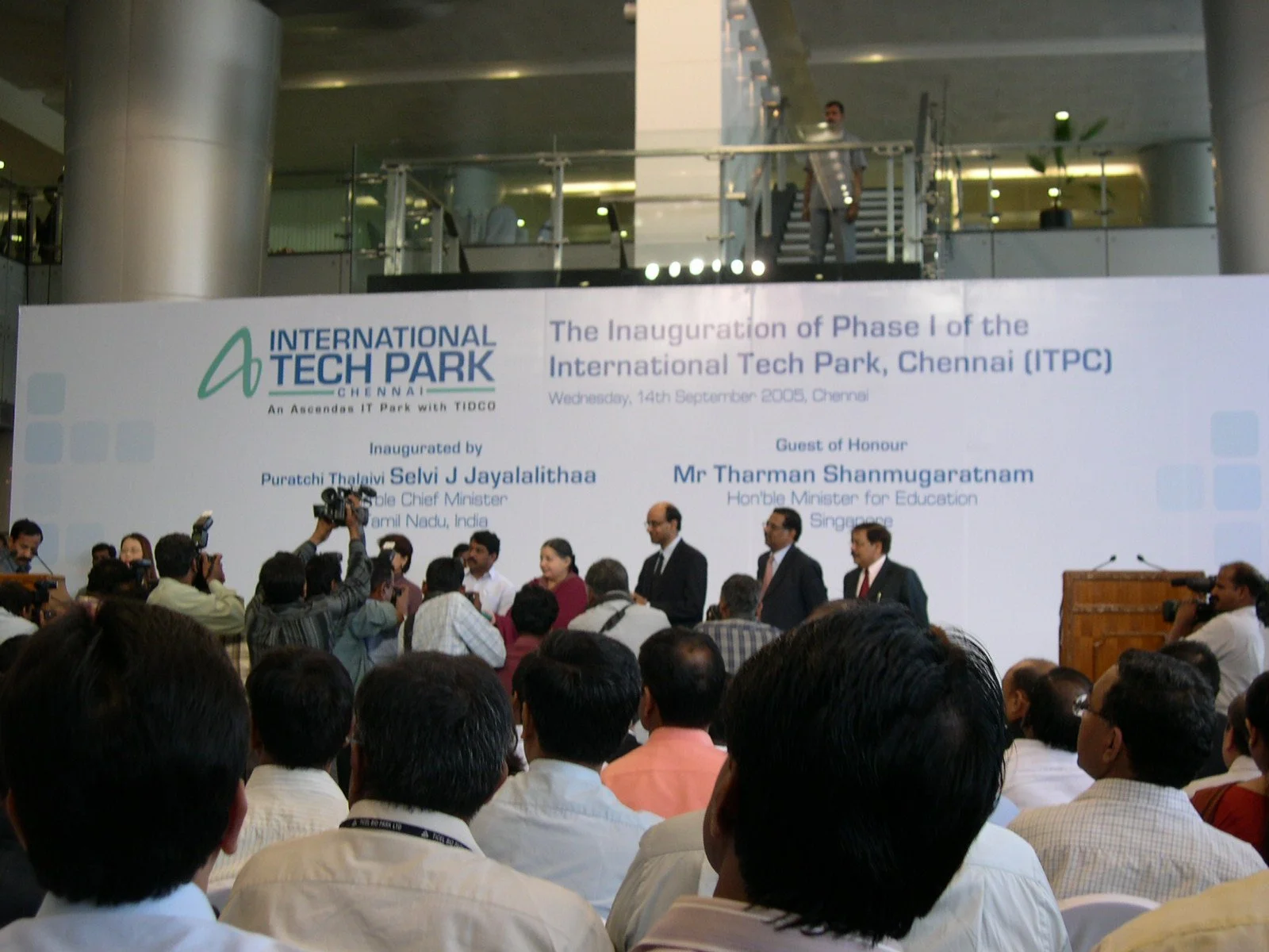 A large crowd attending the inauguration of Phase 1 of the International Tech Park in Chennai, India, with a stage displaying a banner featuring the event details and dignitaries on stage, including the Prime Minister of India and the Hon'ble Ministe