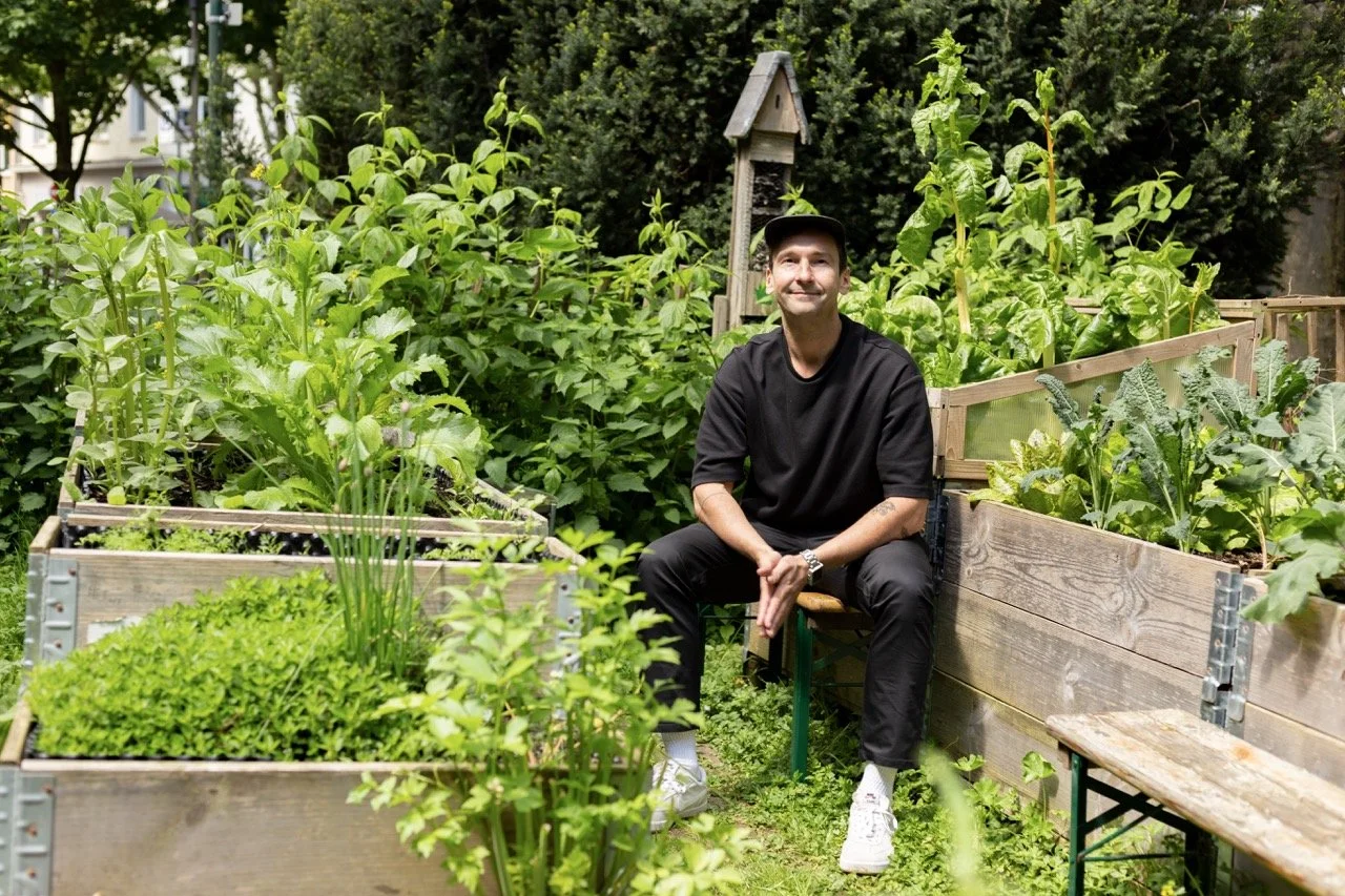 Thomas sitzend im grünen Garten mit schwarzem Tshirt und Cappy